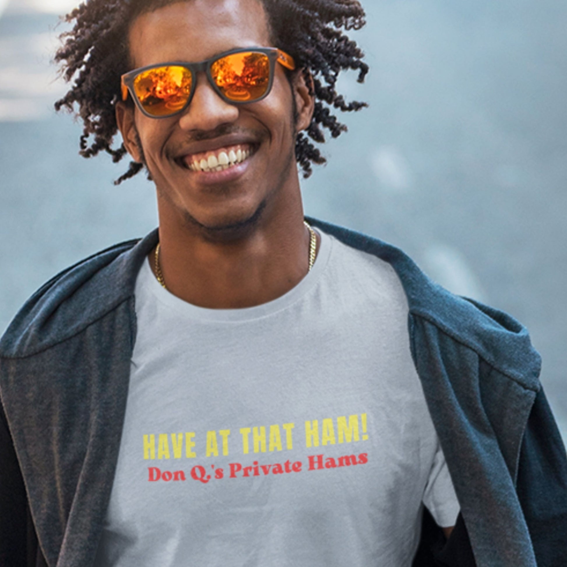 Man wearing sunglasses and a t-shirt with humorous text, standing outdoors.