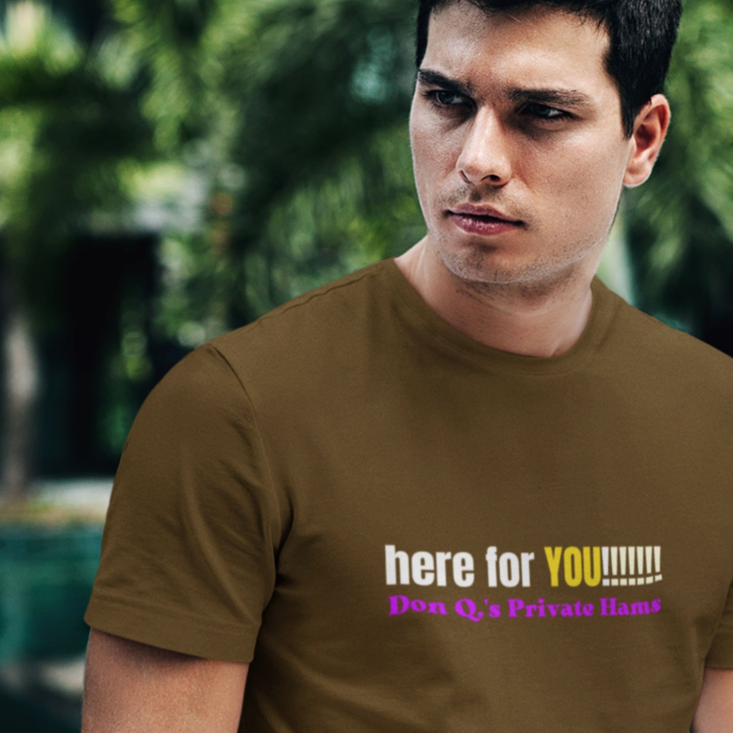 Man wearing a brown t-shirt with colorful text in an outdoor setting.