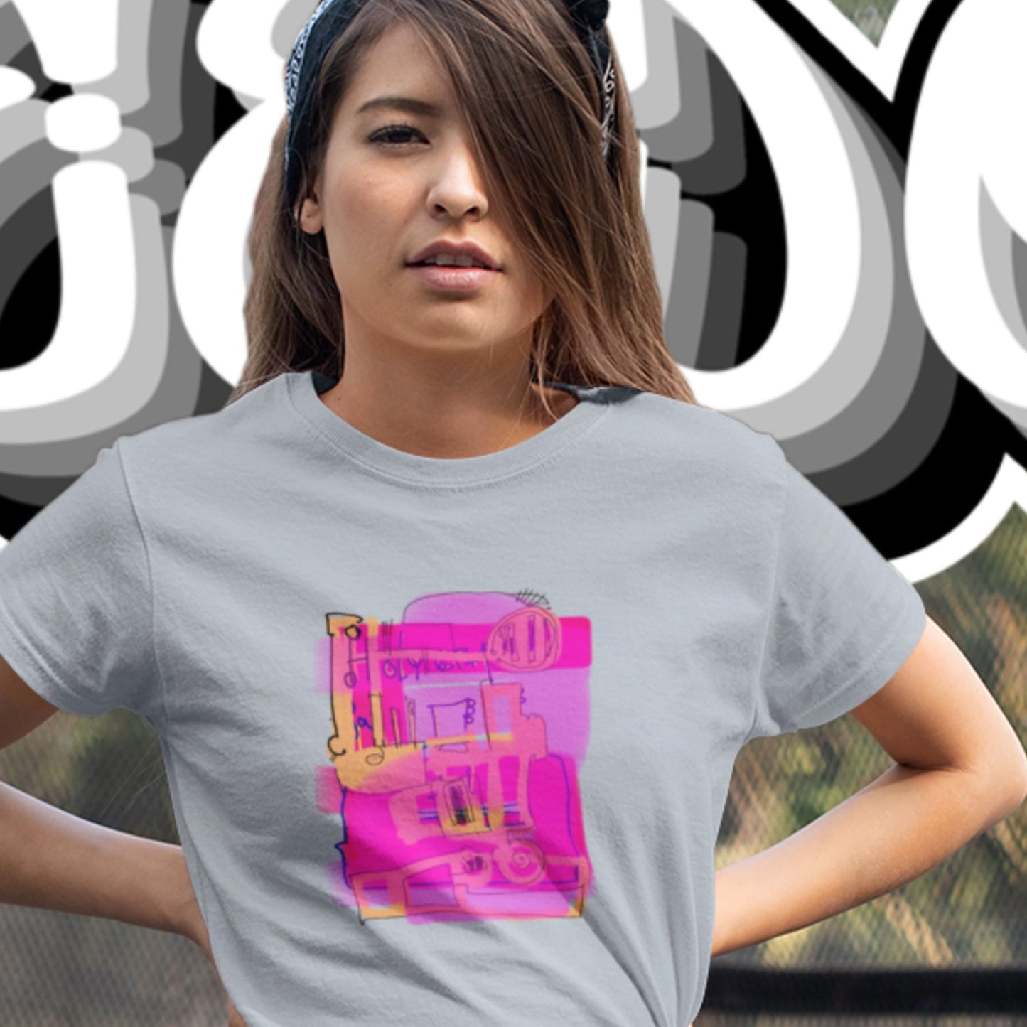Woman wearing a blue t-shirt with a colorful abstract drawing in front of a wall of graffiti.