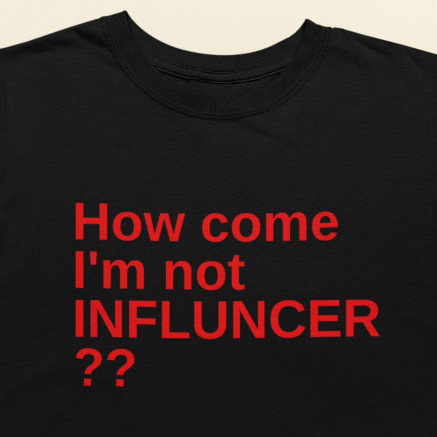Black t-shirt with red text 'How come I'm not INFLUNCER ??' on a beige background