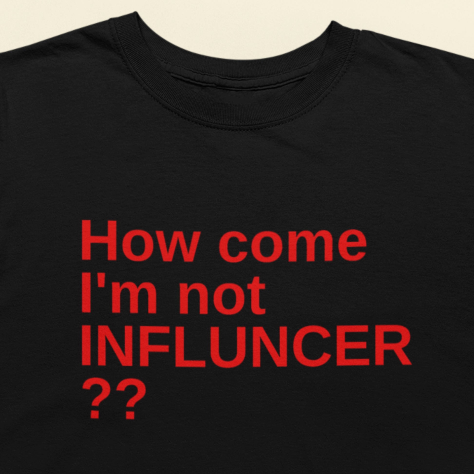Black t-shirt with red text 'How come I'm not INFLUNCER ??' on a beige background