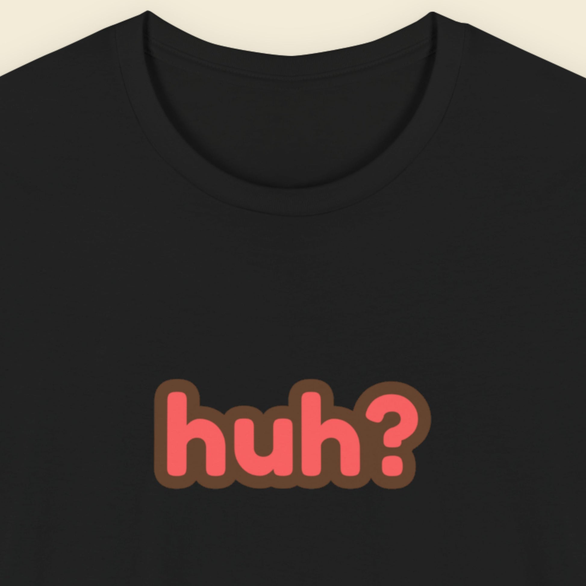 Black t-shirt with multicolored 'huh?' text on a beige background.