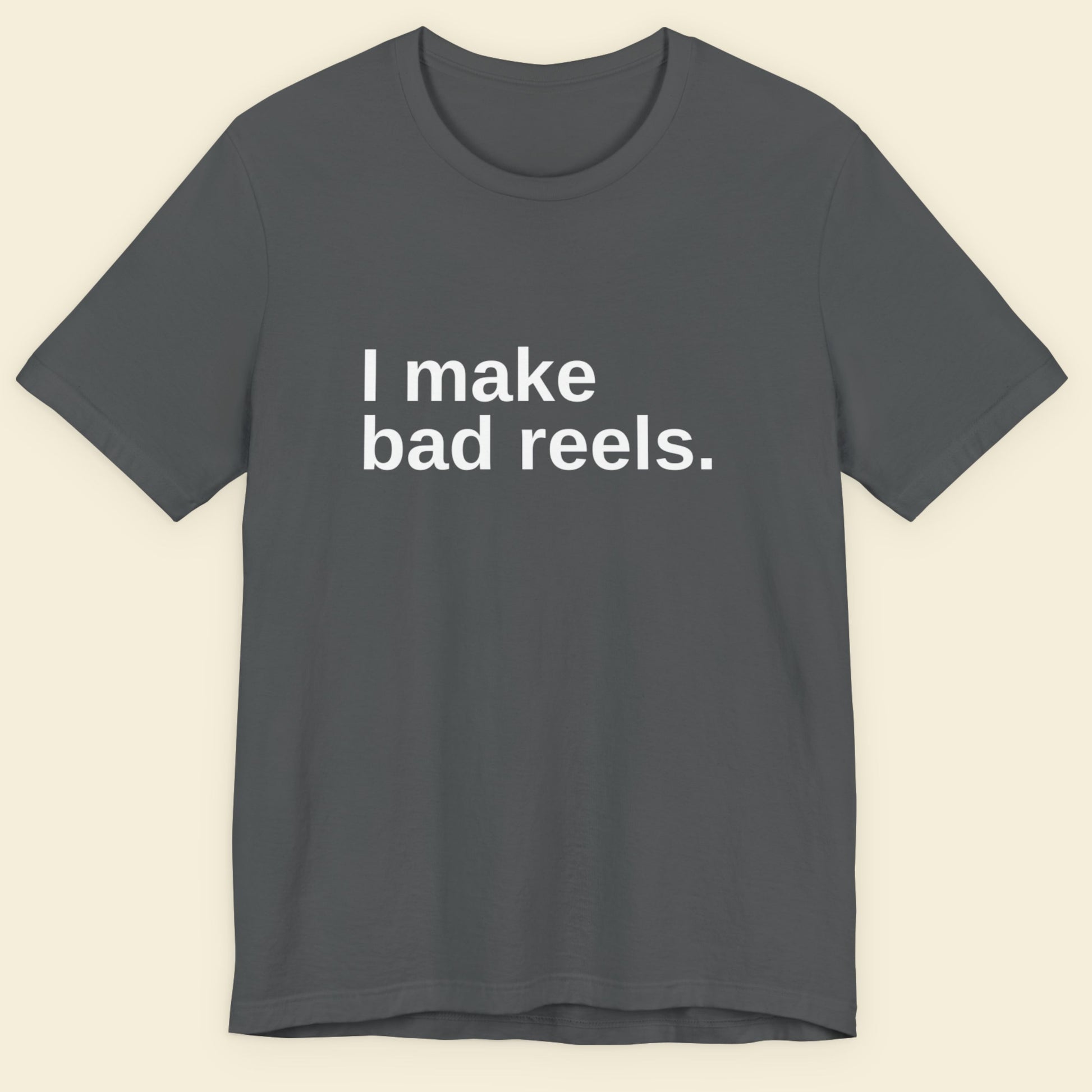 Gray t-shirt with 'I make bad reels' text on a beige background.
