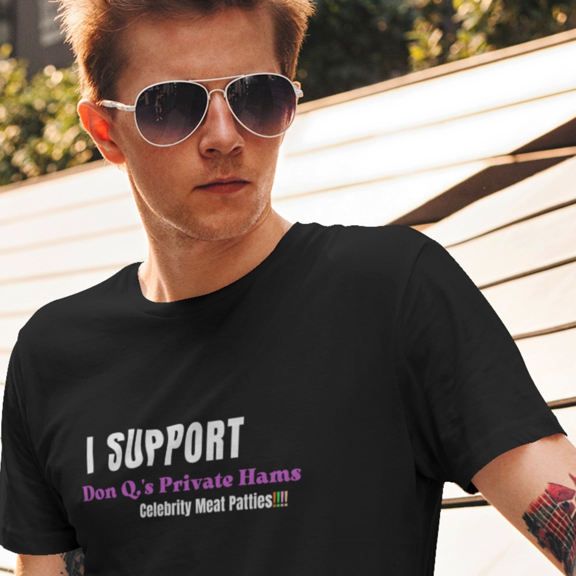 Man wearing a black t-shirt with humorous text outdoors.
