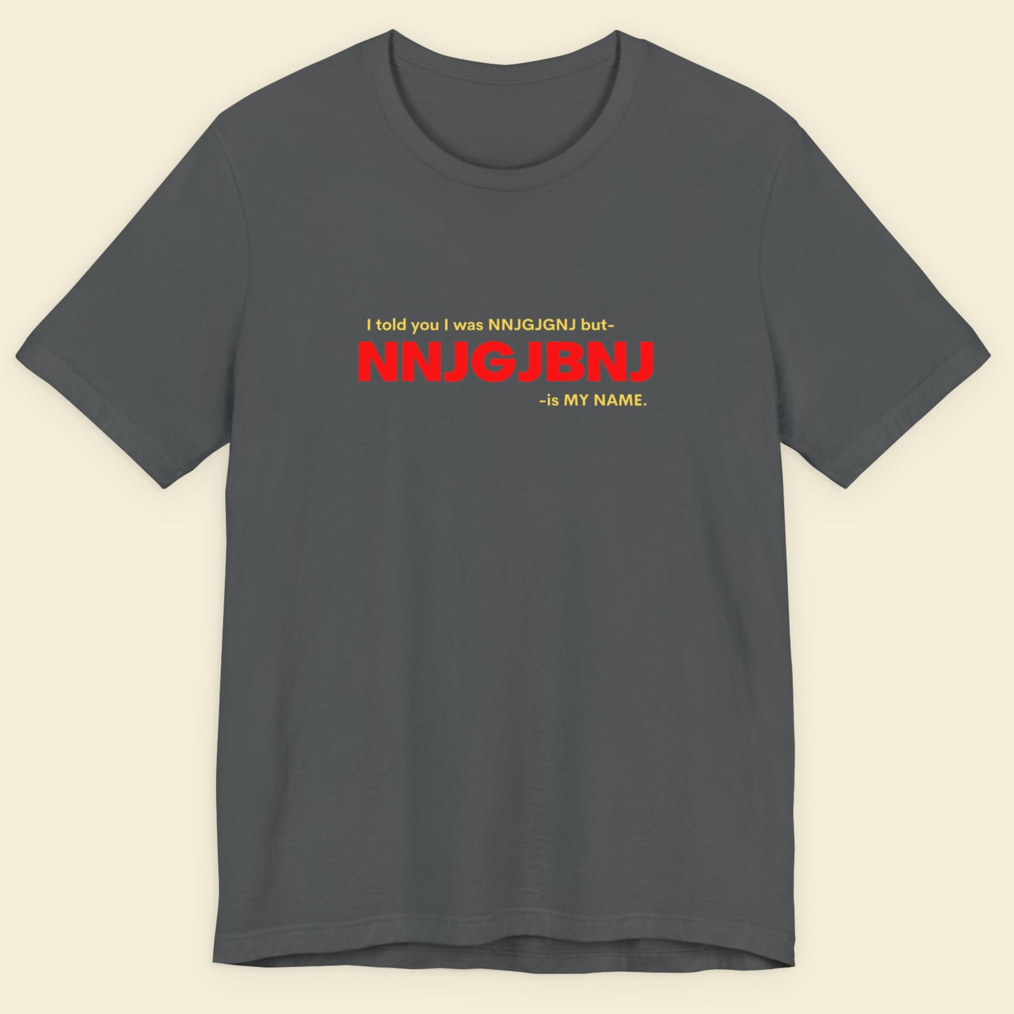 Grey t-shirt with humorous colorful text on a beige background.