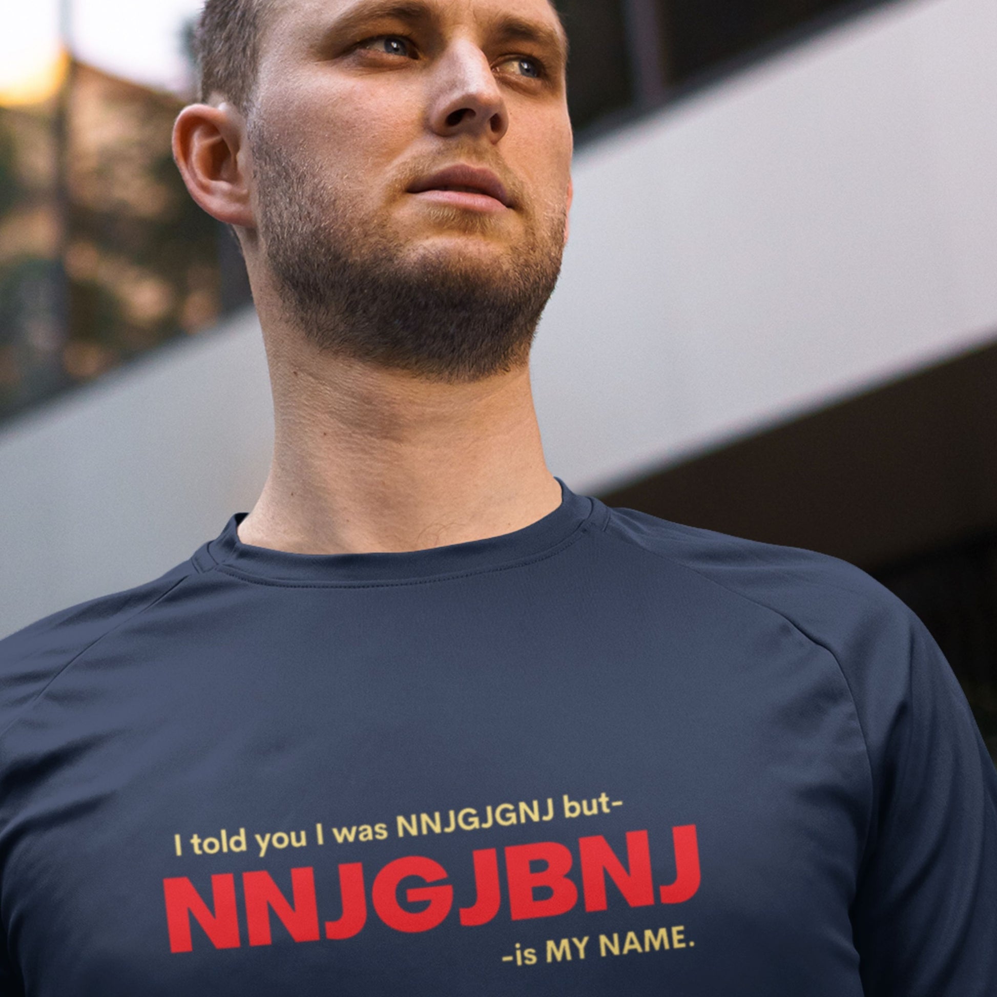 Man wearing a navy blue t-shirt with text on it, standing outdoors.