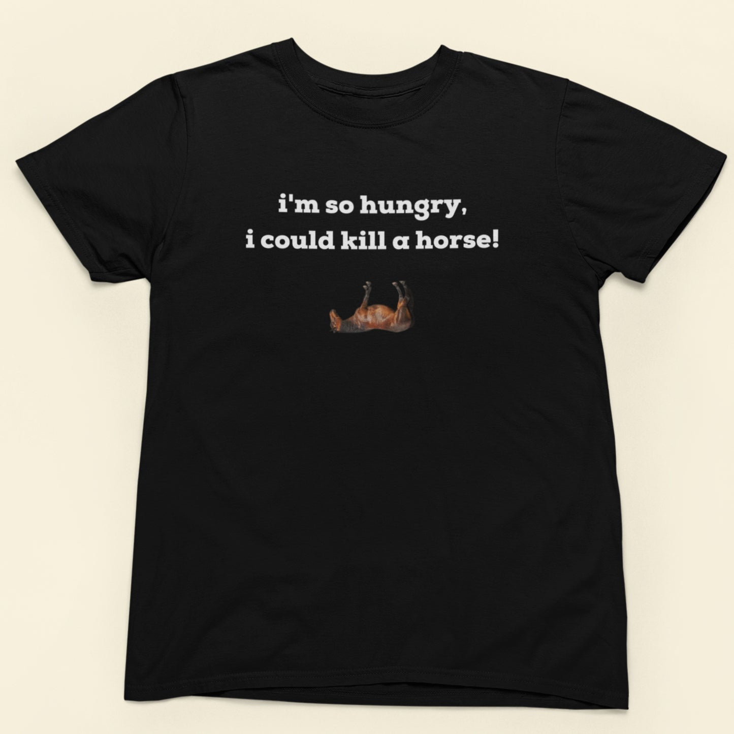 Black t-shirt with humorous text and graphic on a beige background