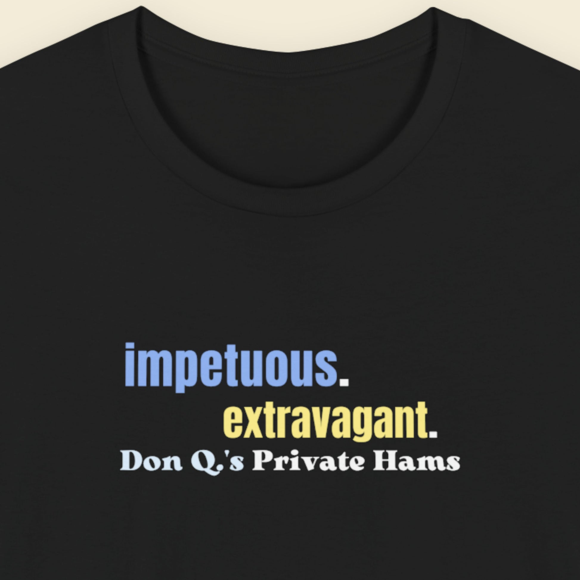 Black t-shirt with multicolored 'impetuous. extravagant.' text on a beige background.