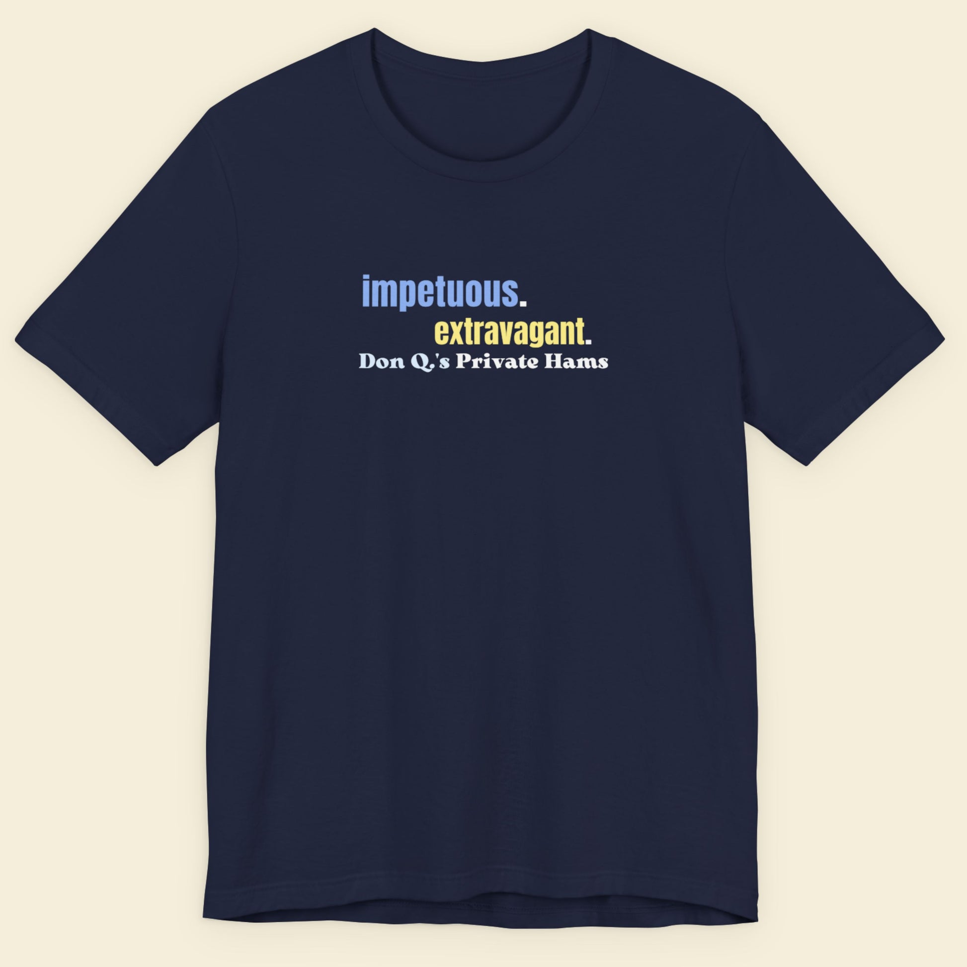 Navy blue t-shirt with multicolored 'impetuous. extravagant.' text on a beige background.