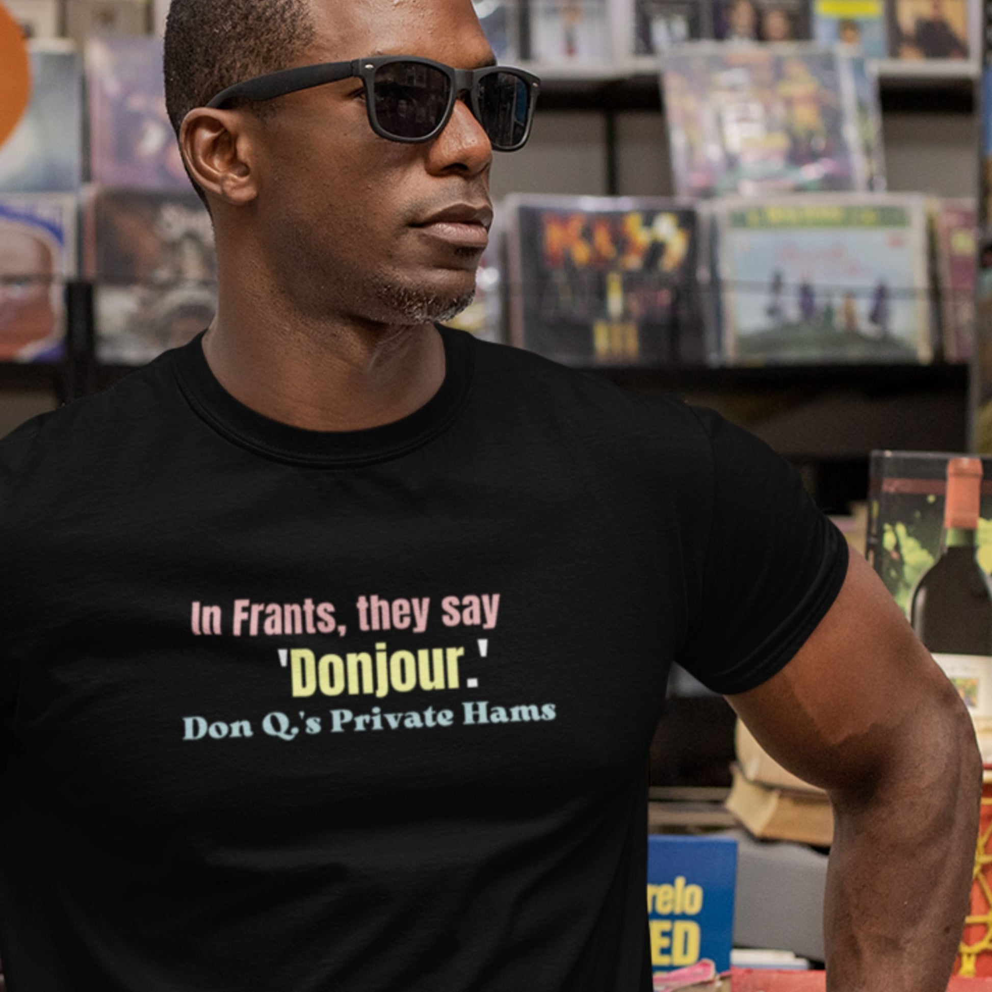 Man wearing a black t-shirt with humorous colorful text in a collectibles store.