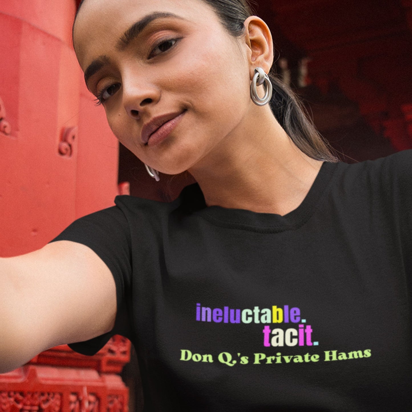Woman wearing a black t-shirt with colorful text in front of a red background.