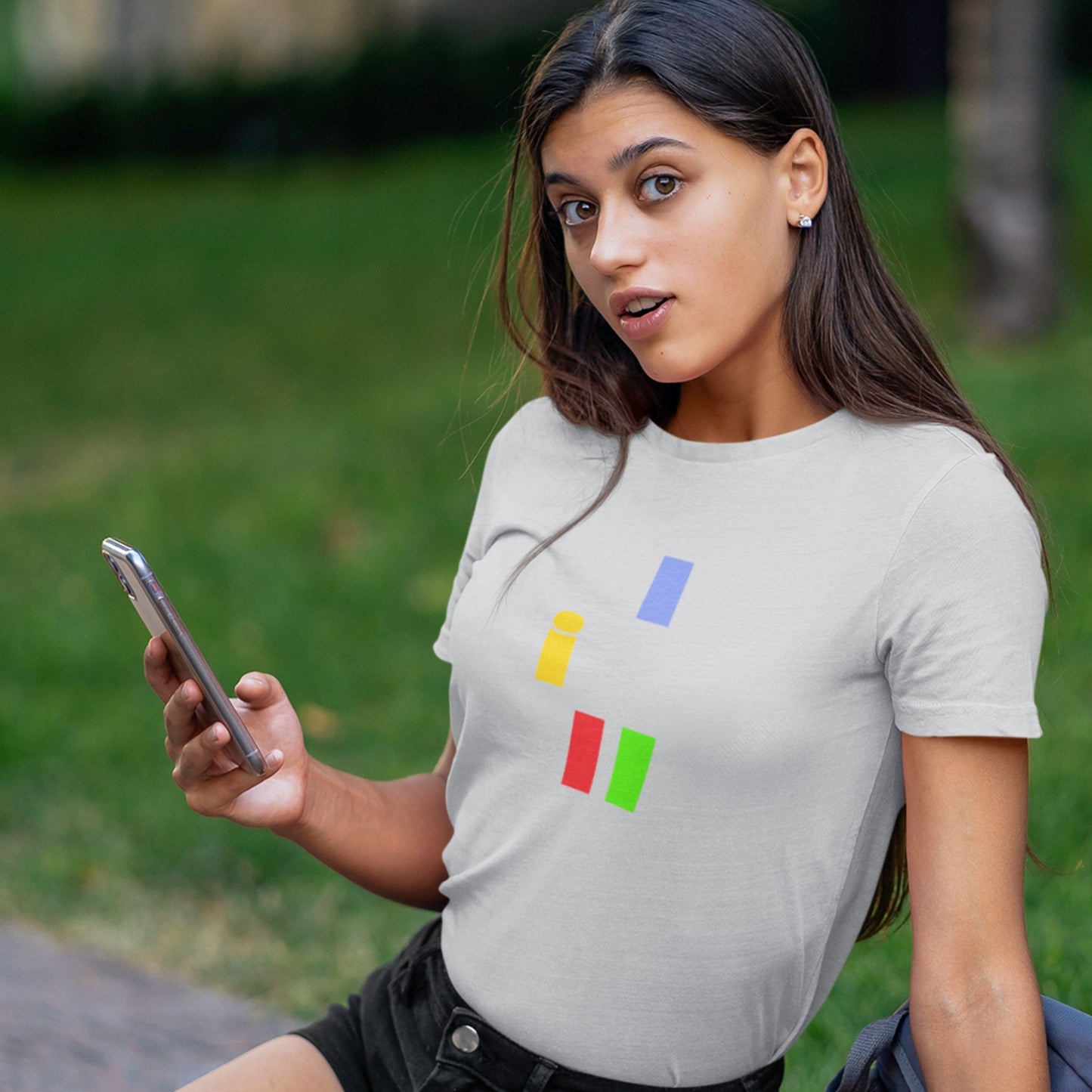 Woman wearing a grey t-shirt with colorful abstract shapes in the park.