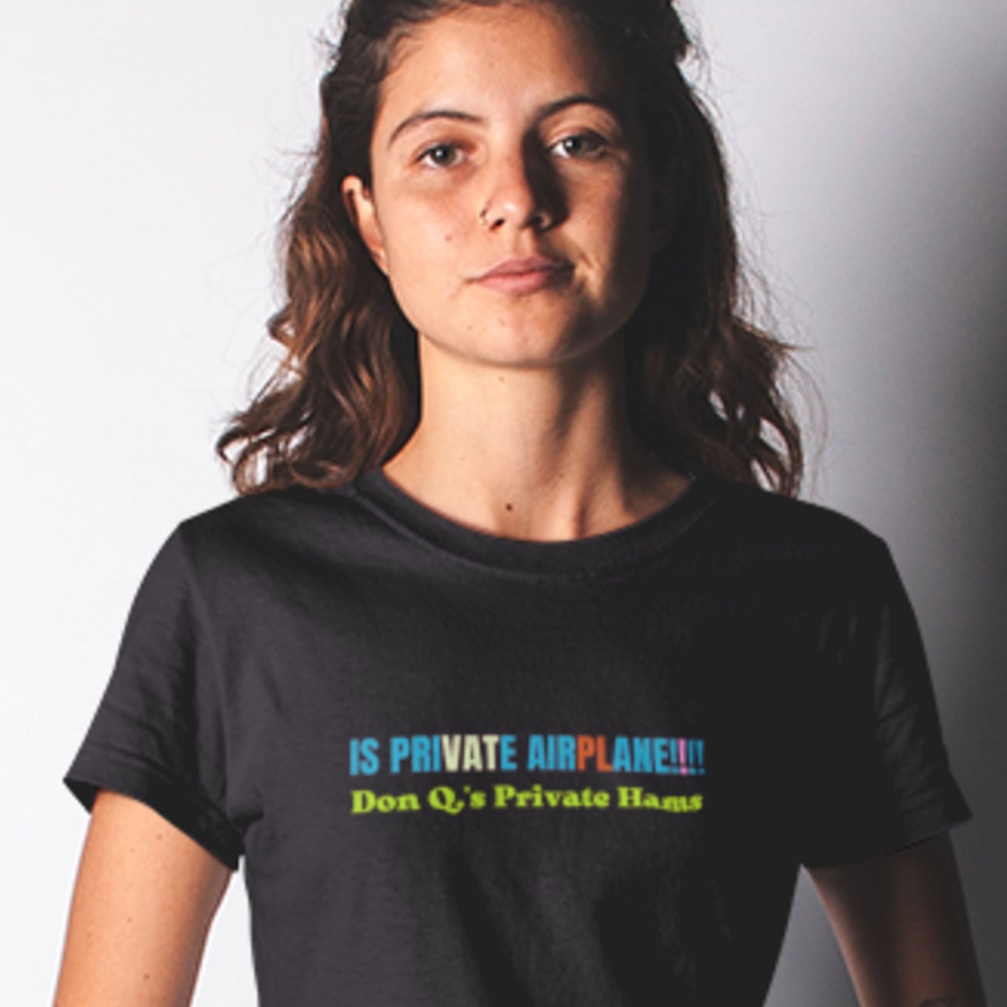 Person wearing a black t-shirt with colorful text on a plain background