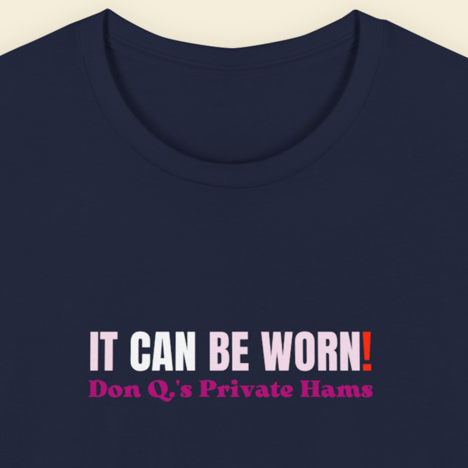 Navy blue t-shirt with humorous text design on a beige background.