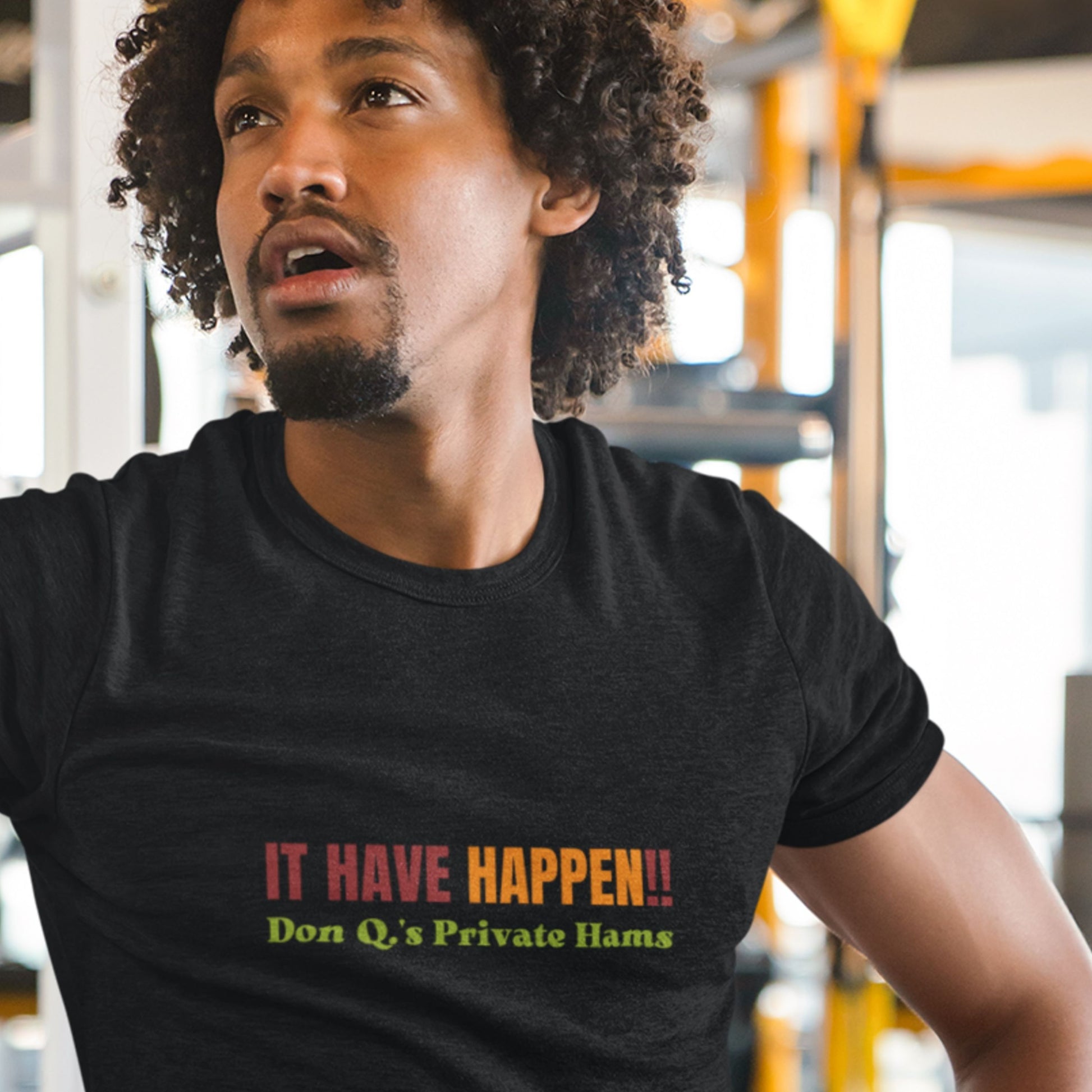 Man wearing a black t-shirt with colorful text in an indoor setting.