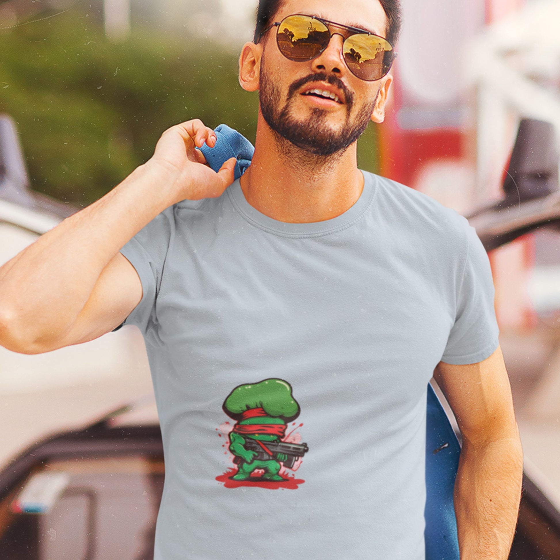 Man wearing a gray t-shirt with a green character design outdoors
