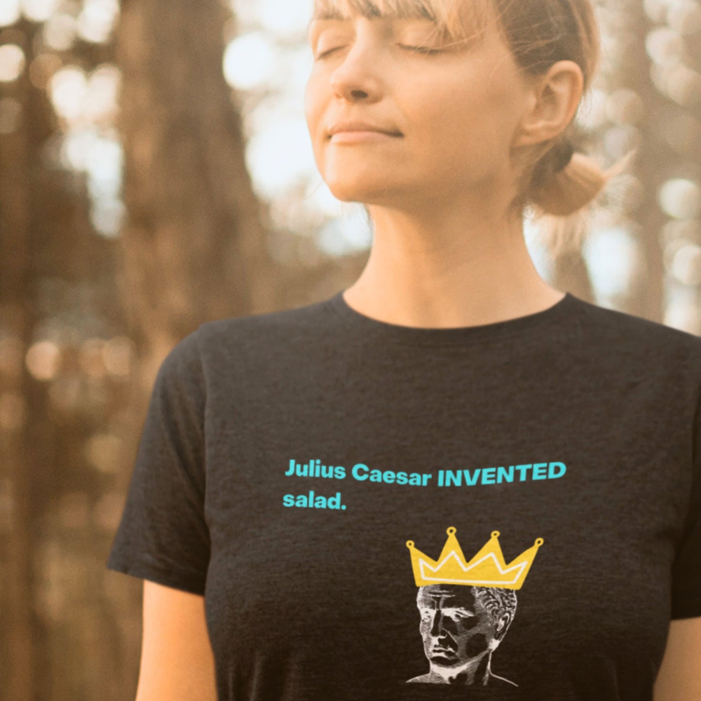 Person wearing a black t-shirt with a graphic and text in a forest setting