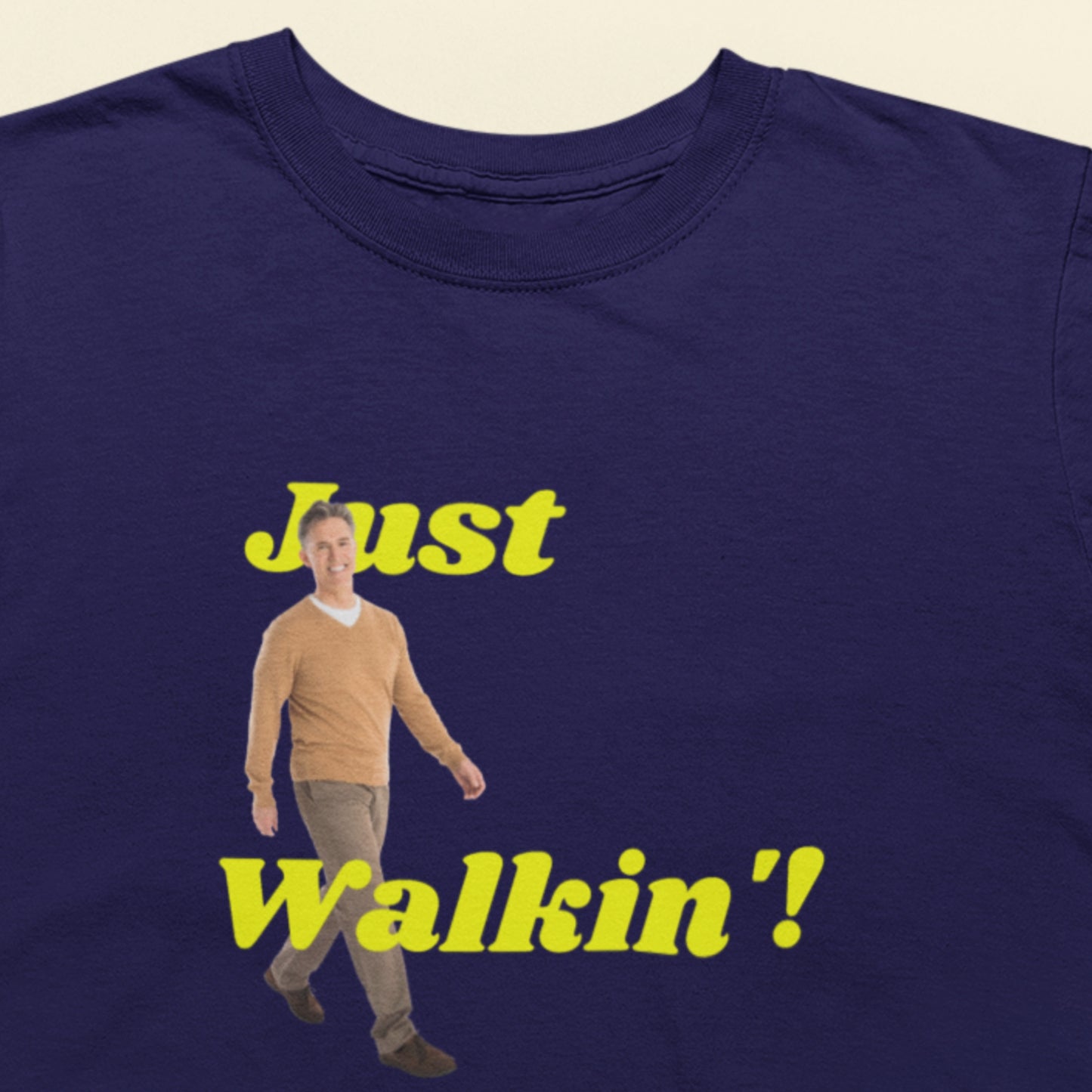 Navy blue t-shirt with a graphic of a man and text 'Just Walkin'' on a beige background