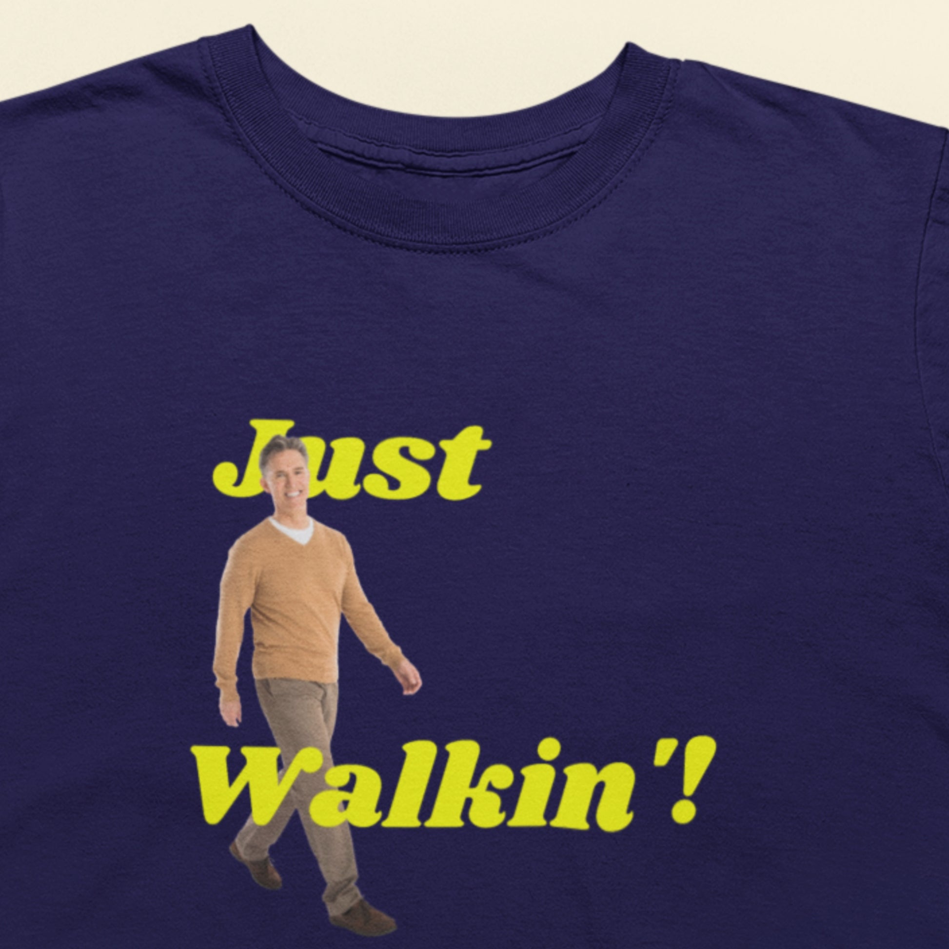 Navy blue t-shirt with a graphic of a man and text 'Just Walkin'' on a beige background