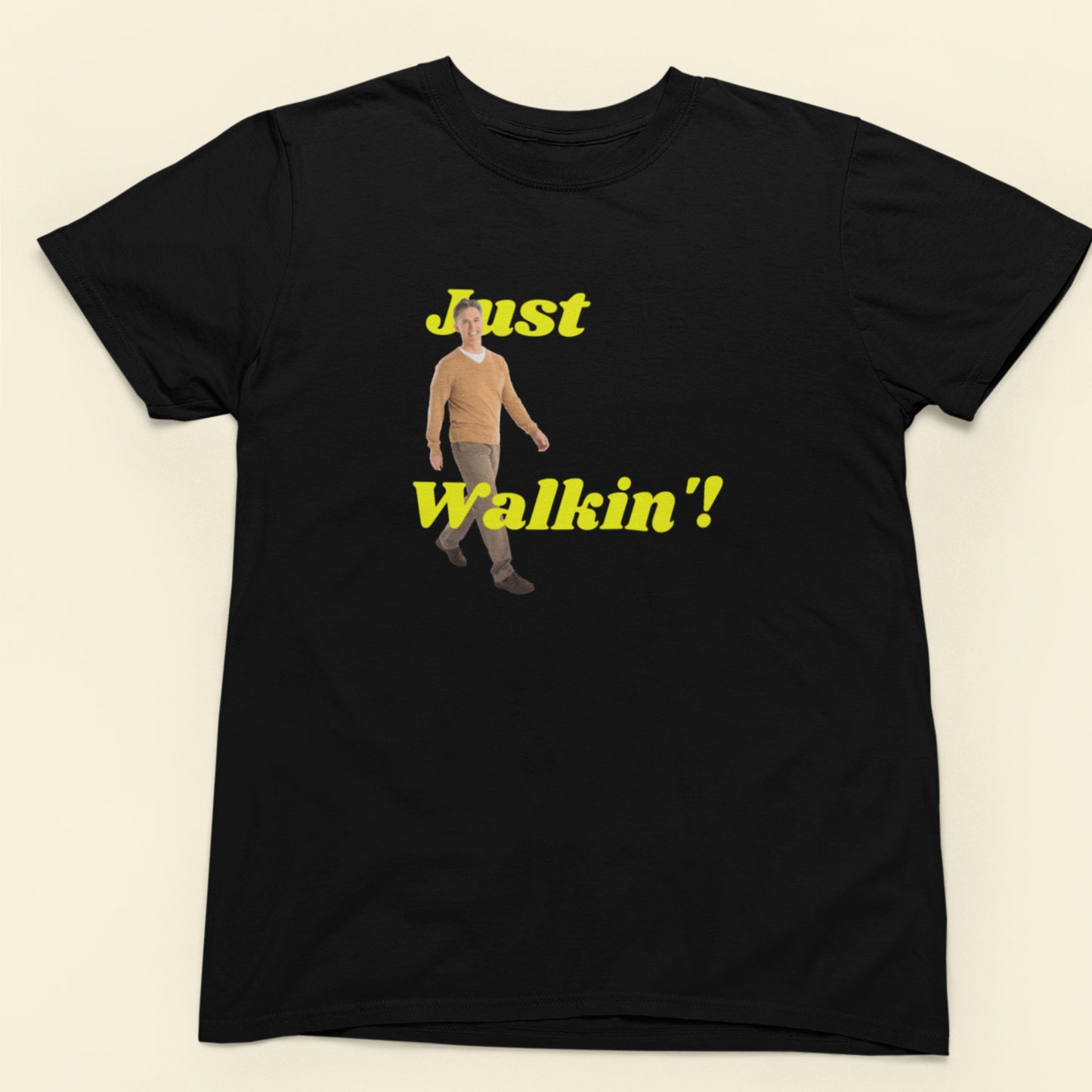 Black t-shirt with a graphic of a person and text 'Just Walkin'' on a beige background