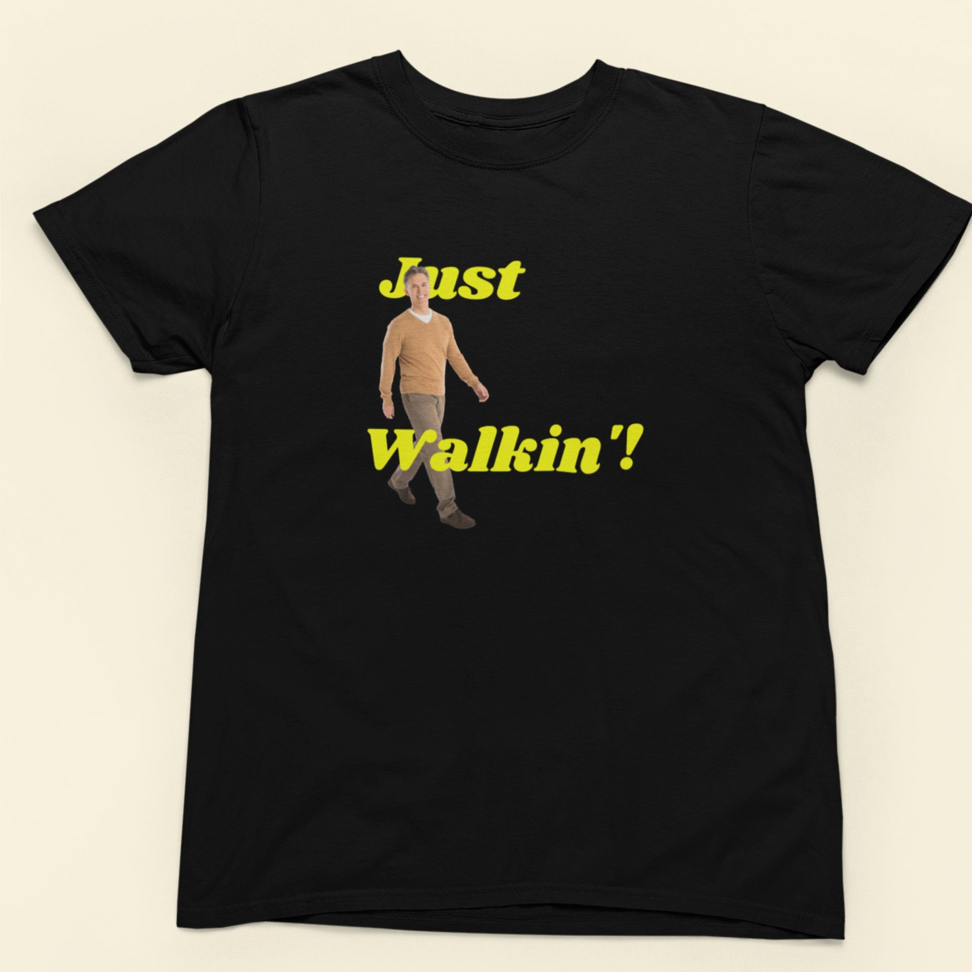 Black t-shirt with a graphic of a person and text 'Just Walkin'' on a beige background