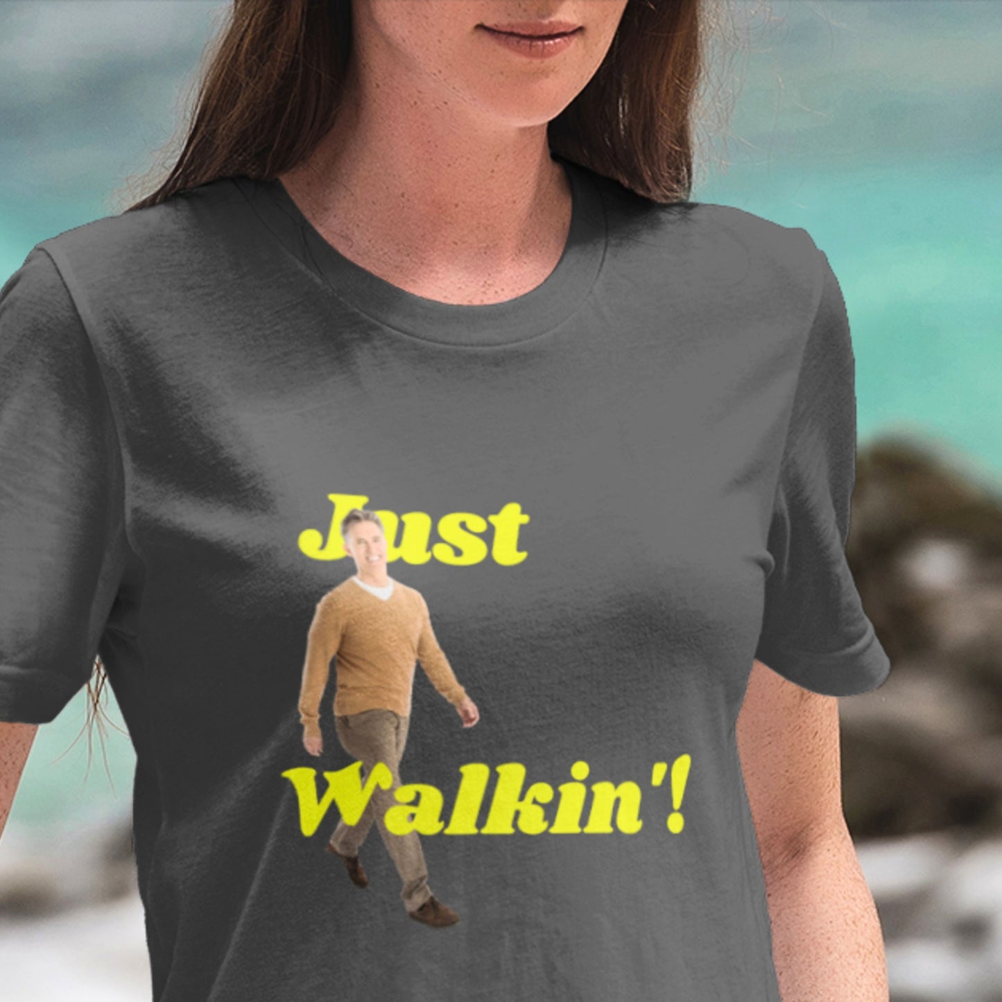 Person wearing a t-shirt with a graphic and text 'Just Walkin!' against a blurred natural background.