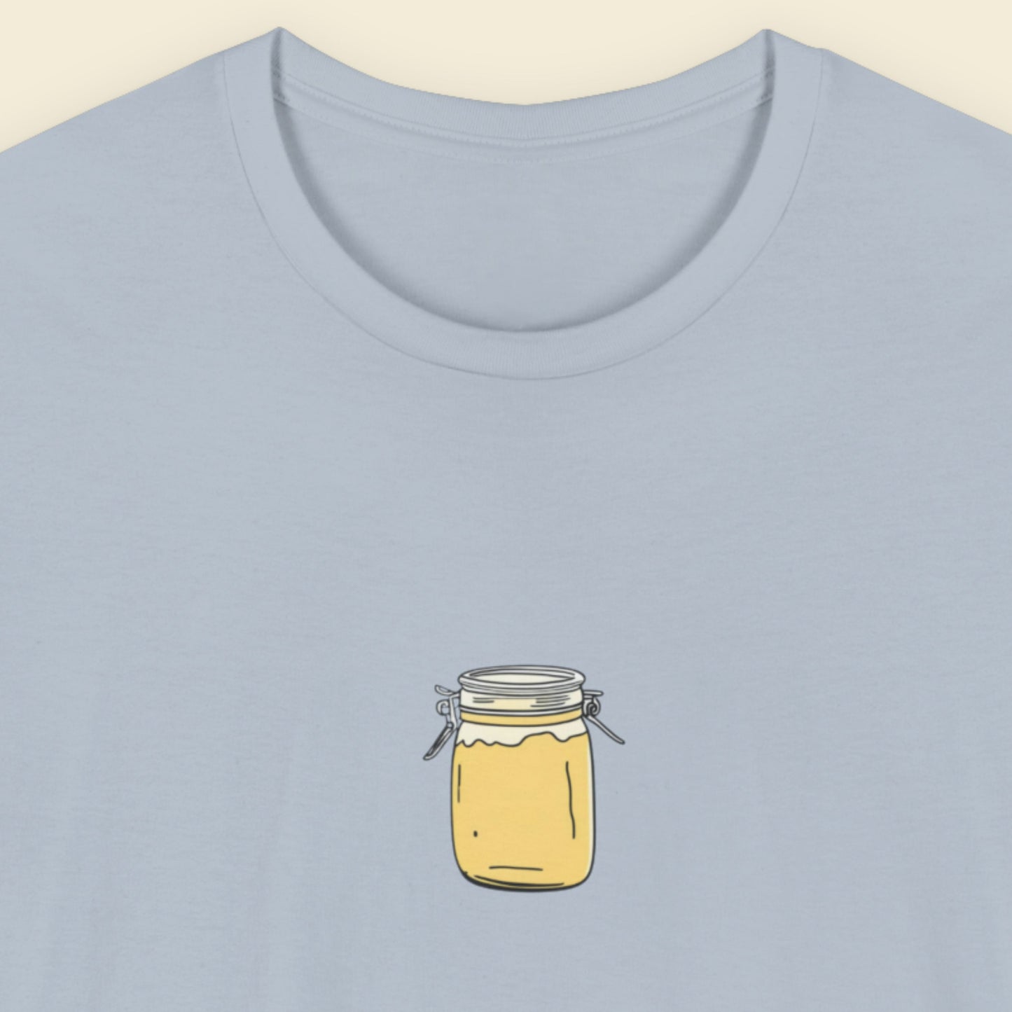 Light blue t-shirt with a drawing of a little snap top yellow jar.