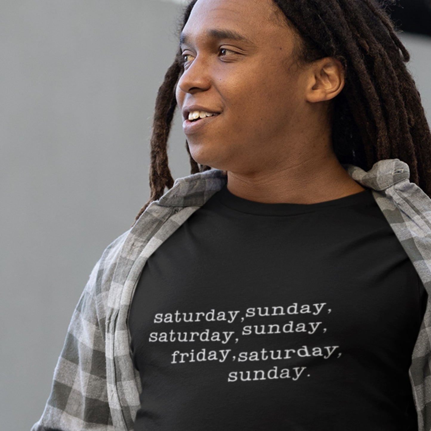 Man wearing a black shirt with humorous off-center text outside and smiling.