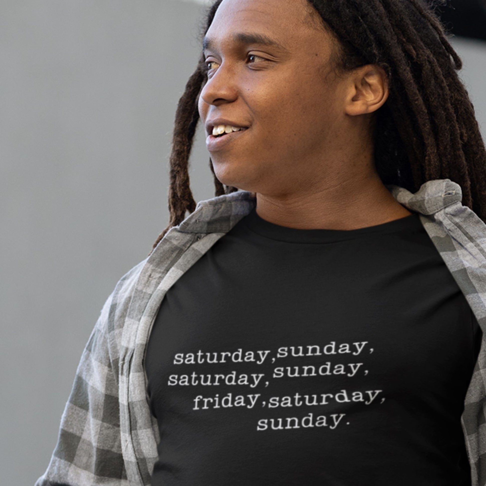 Man wearing a black shirt with humorous off-center text outside and smiling.
