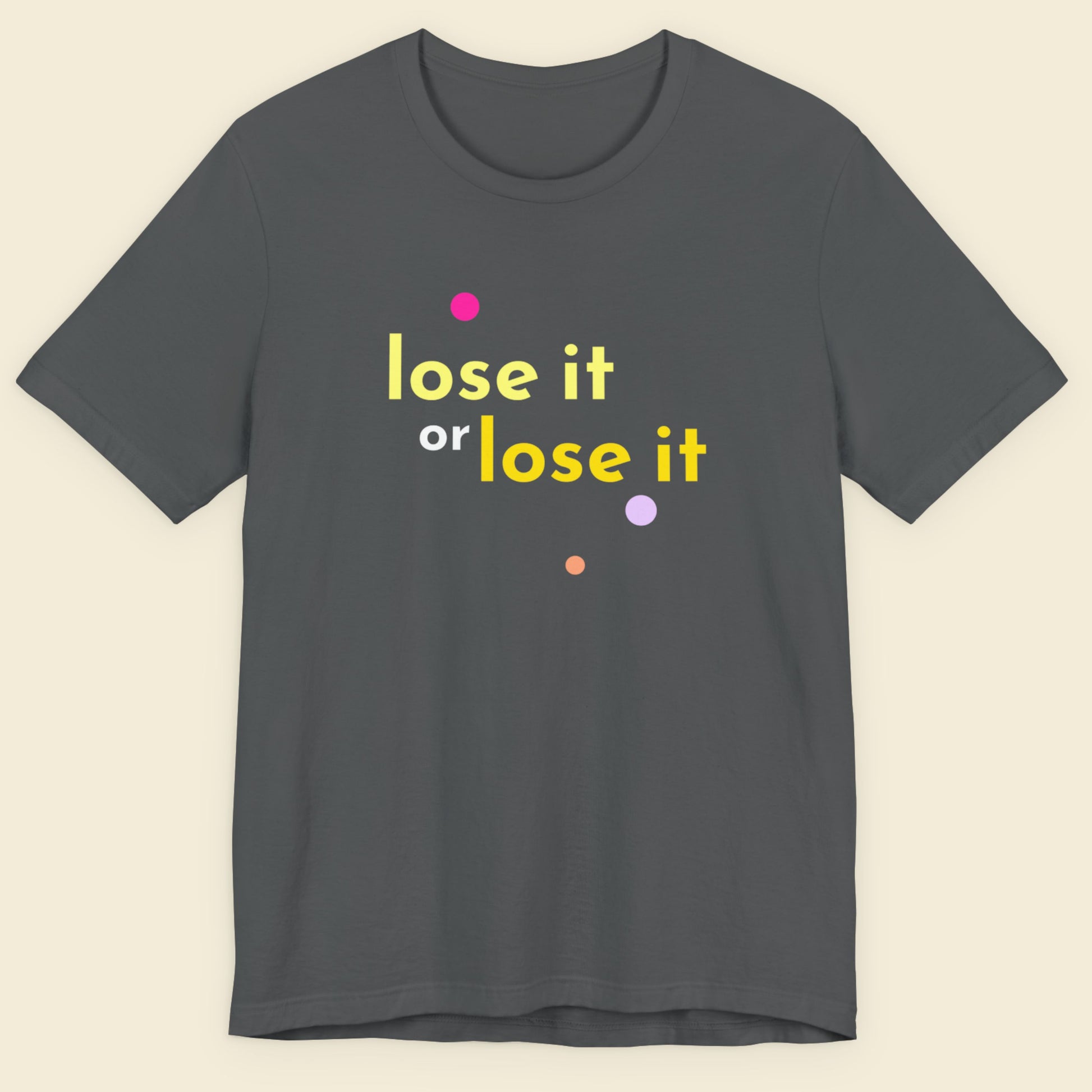 Grey t-shirt with humorous colorful text on a beige background.