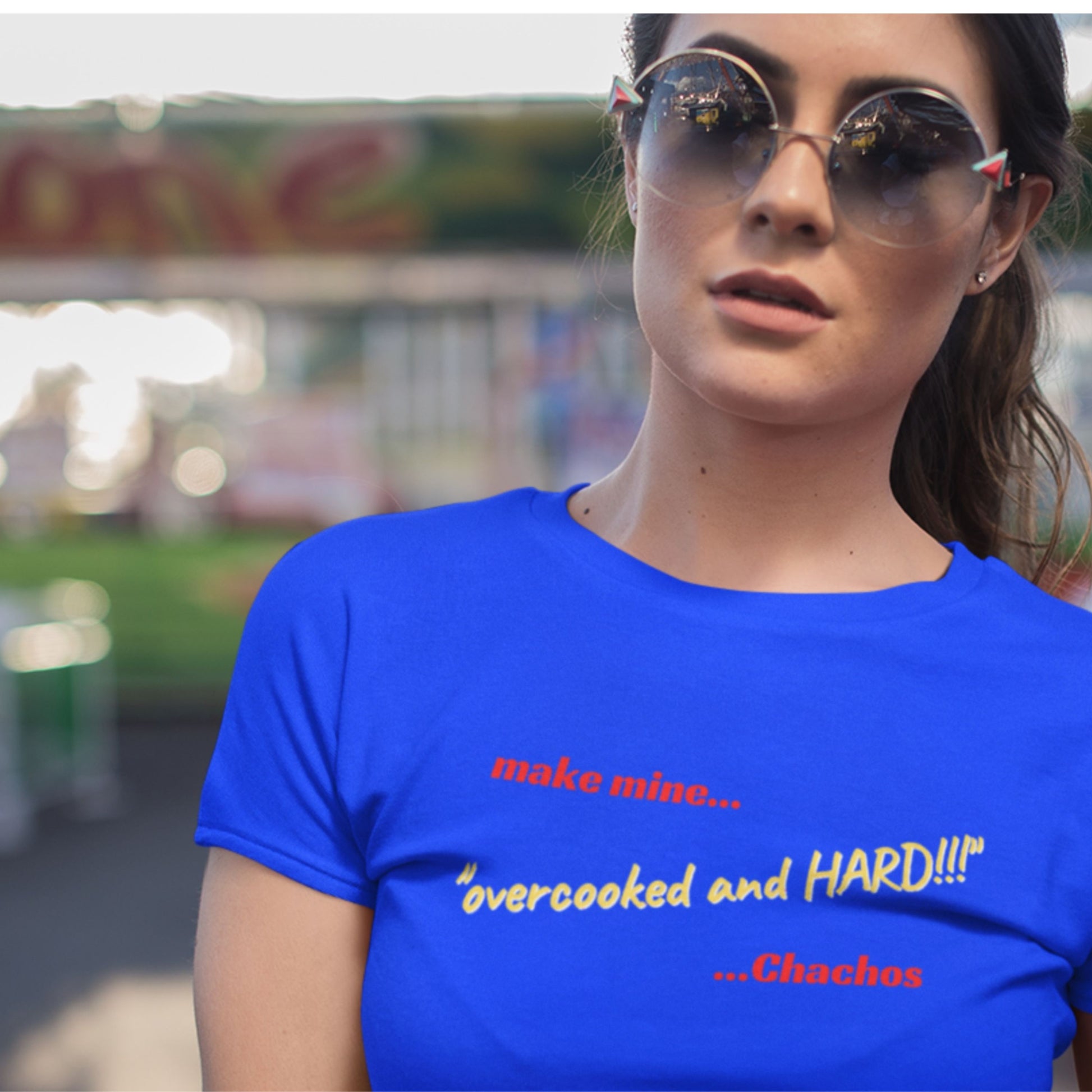 Woman wearing a blue t-shirt with text, outdoors with blurred background.