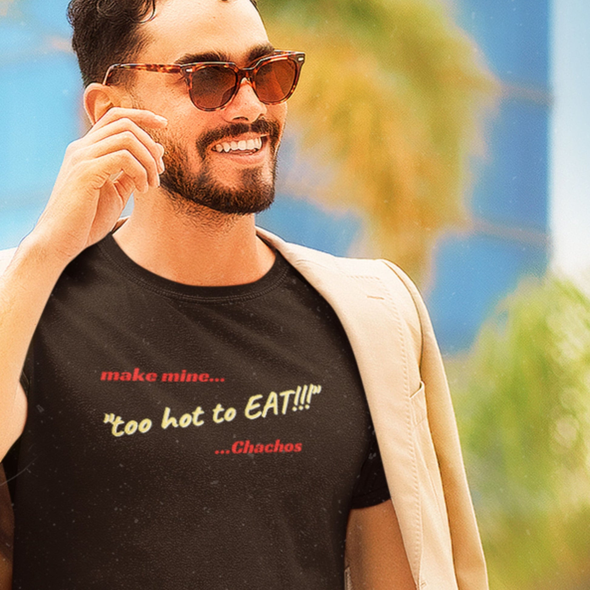Man wearing a black t-shirt with text, standing outdoors with greenery in the background.