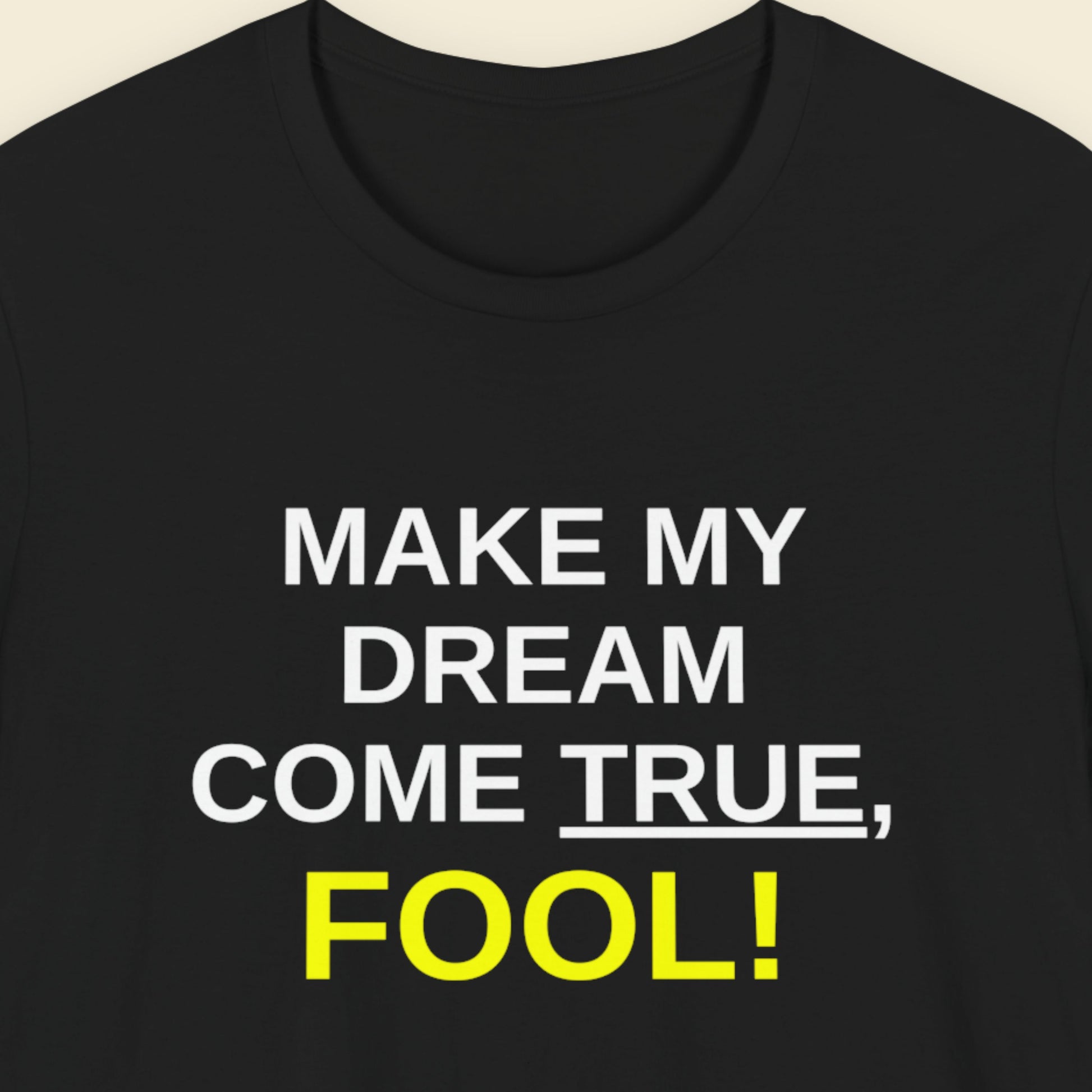 Black t-shirt with white and yellow text on a beige background.