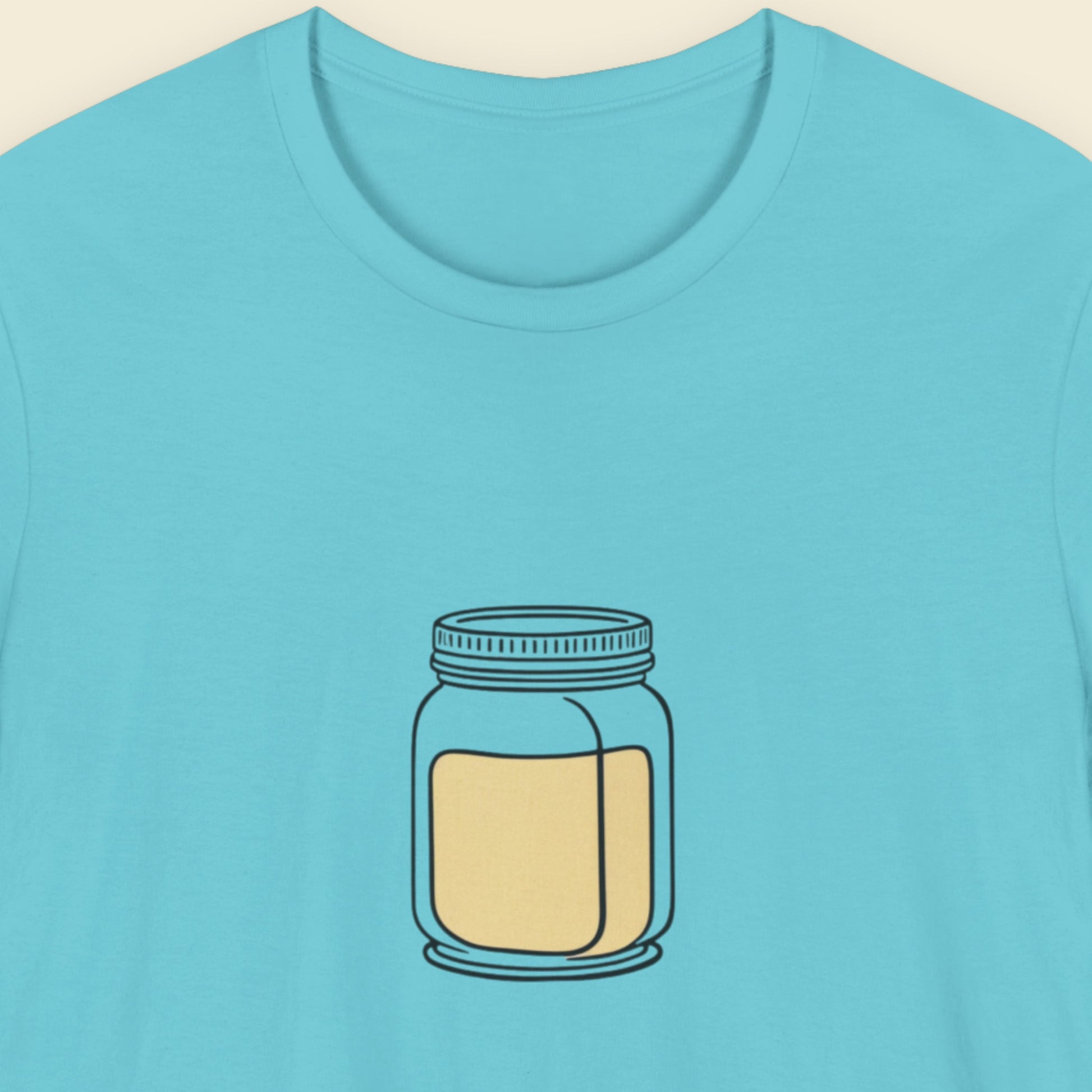 Blue t-shirt with a jar graphic on a beige background.