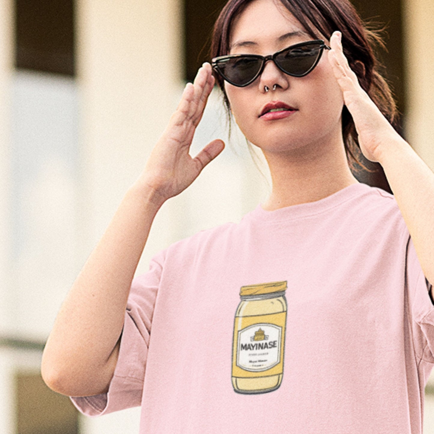 Person wearing a pink t-shirt with a mayonnaise jar graphic, outdoors.