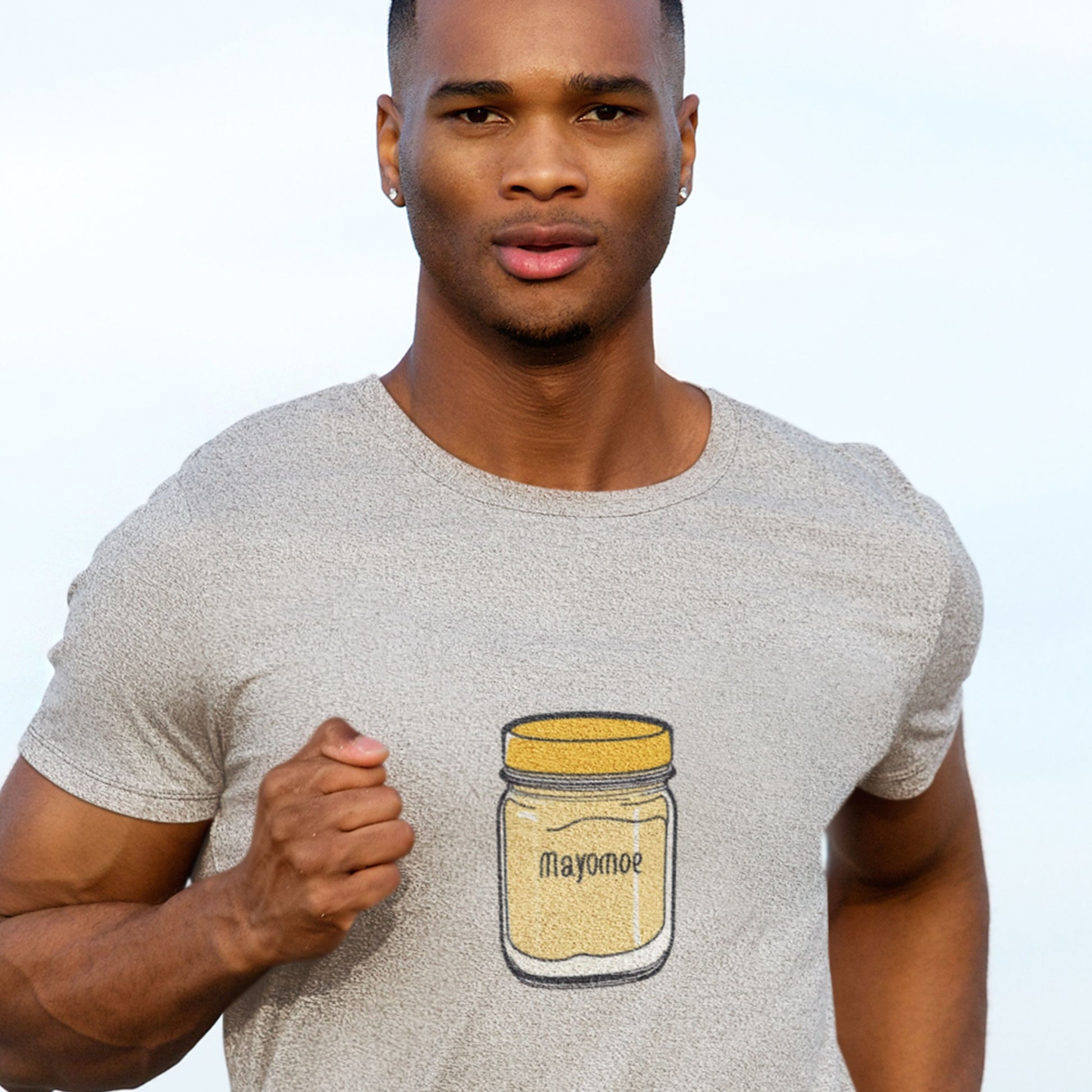 Running man wearing a light grey t-shirt with an illustration of a jar of Mayomoe Dijon mayonnaise outdoors.