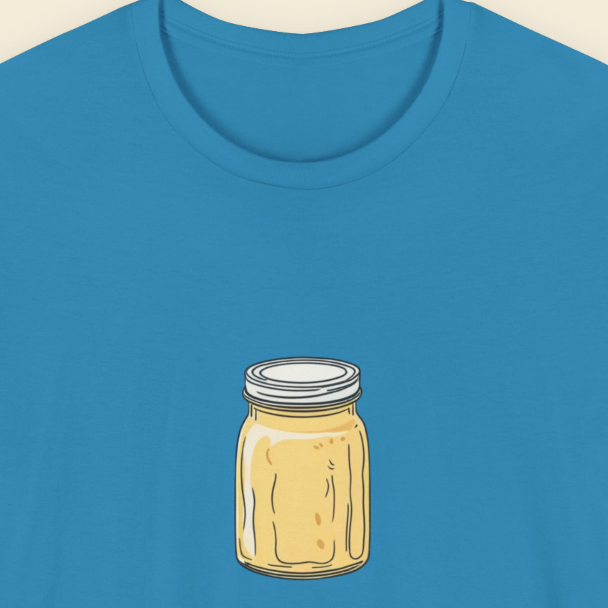 Blue t-shirt with a drawing of a melting yellow jar on a beige background.