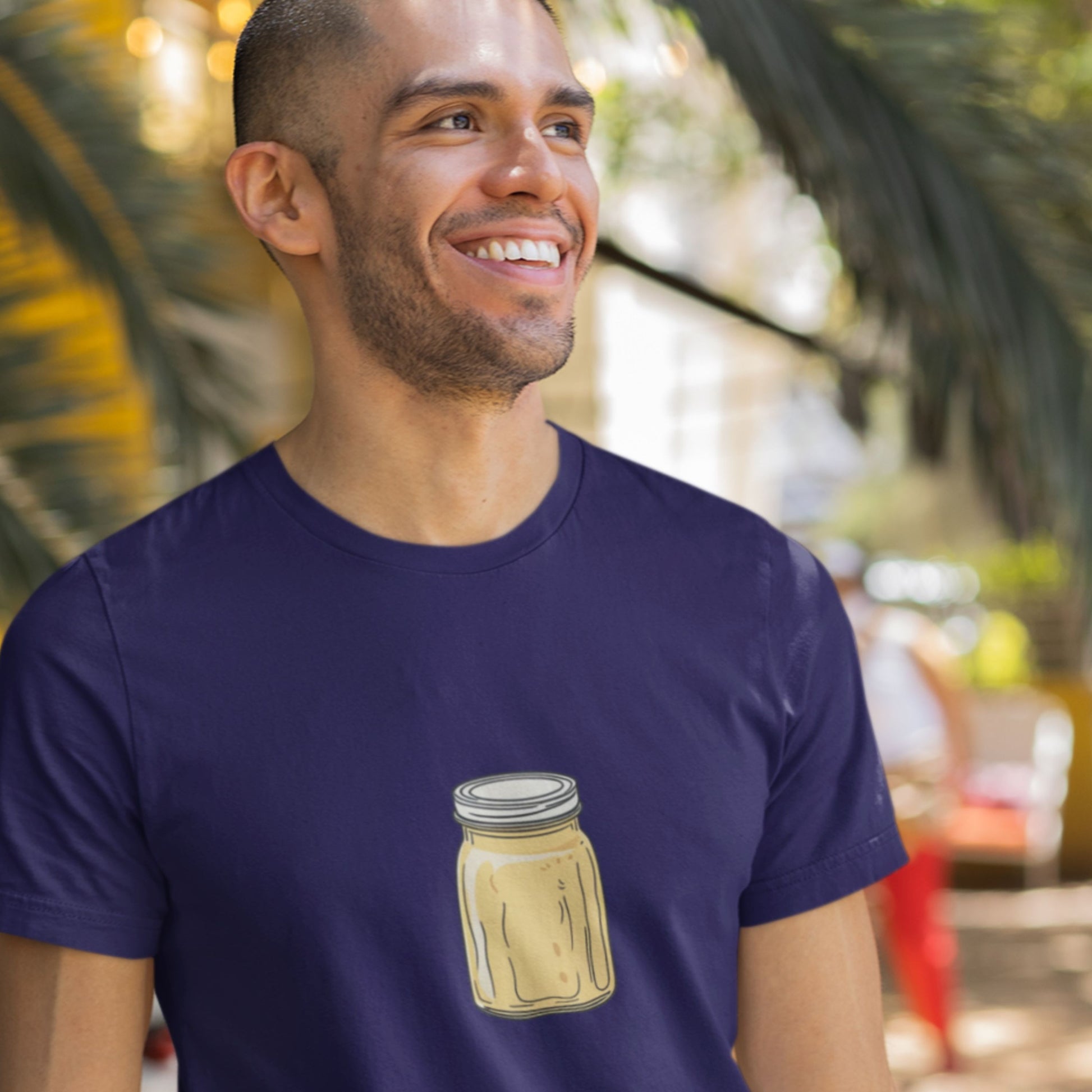 Man wearing a navy blue t-shirt with a drawing of a melting yellow jar outside.