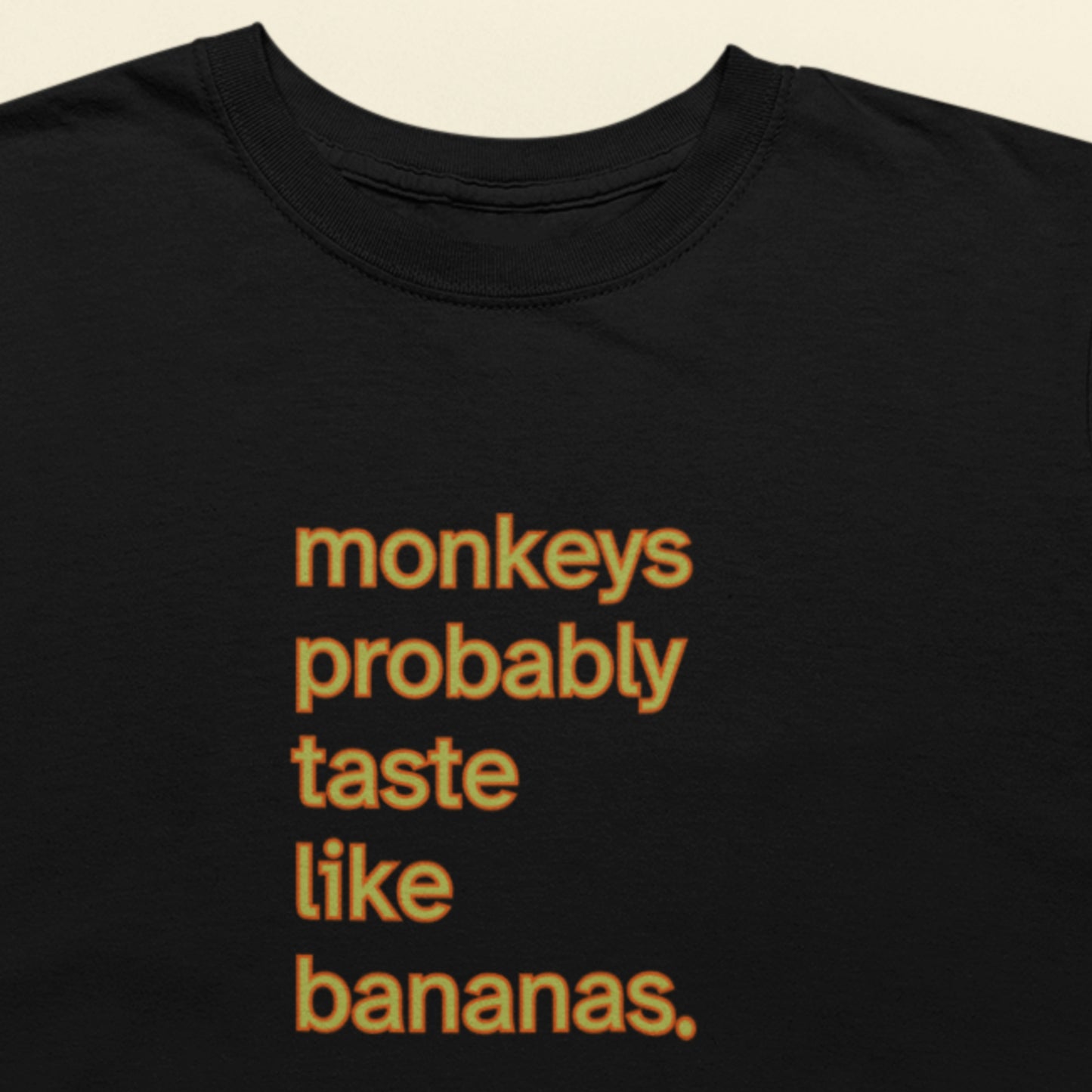 Black t-shirt with orange and yellow 'monkeys probably taste like bananas' text.