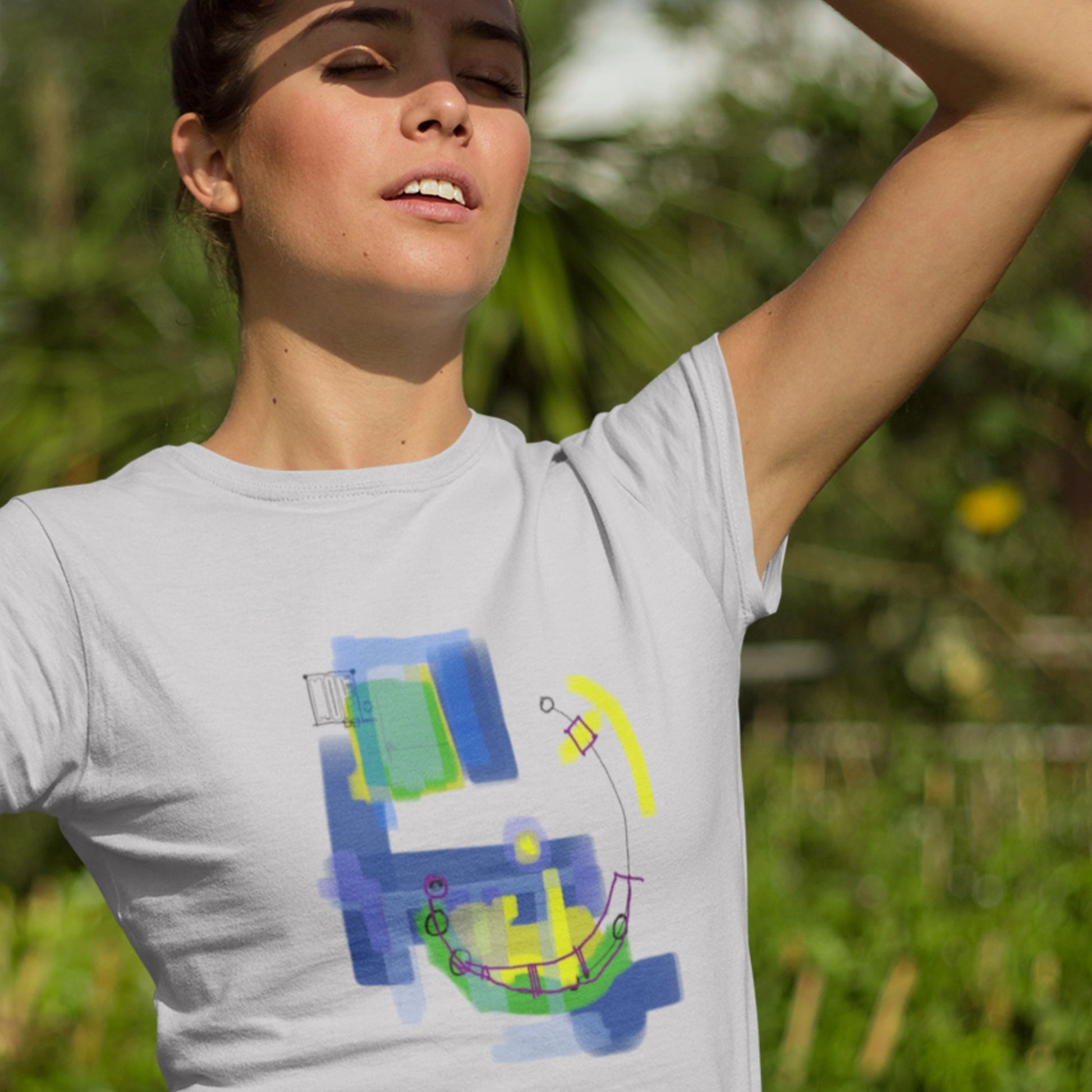 Woman wearing a light grey t-shirt with a colorful abstract drawing outdoors.