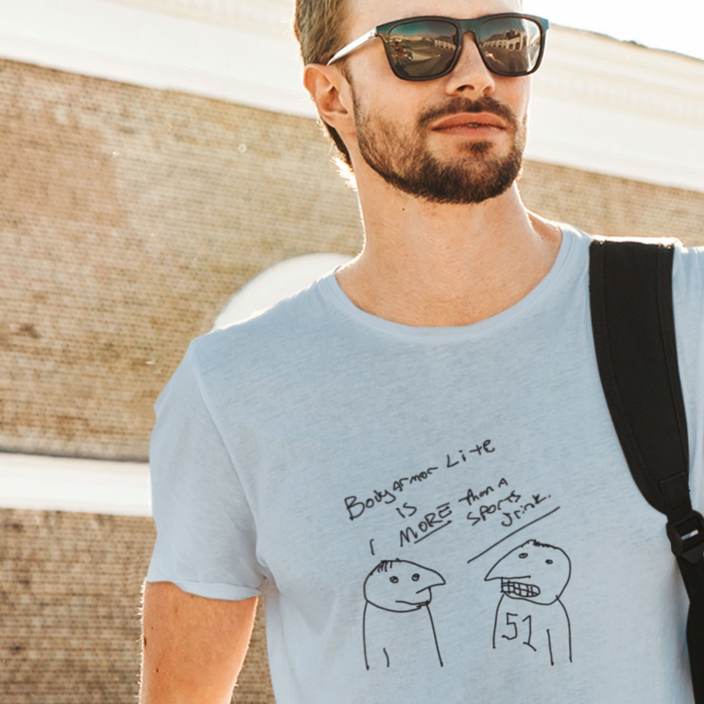 Cool guy wearing a light blue t-shirt with a line drawing in front of a wood.