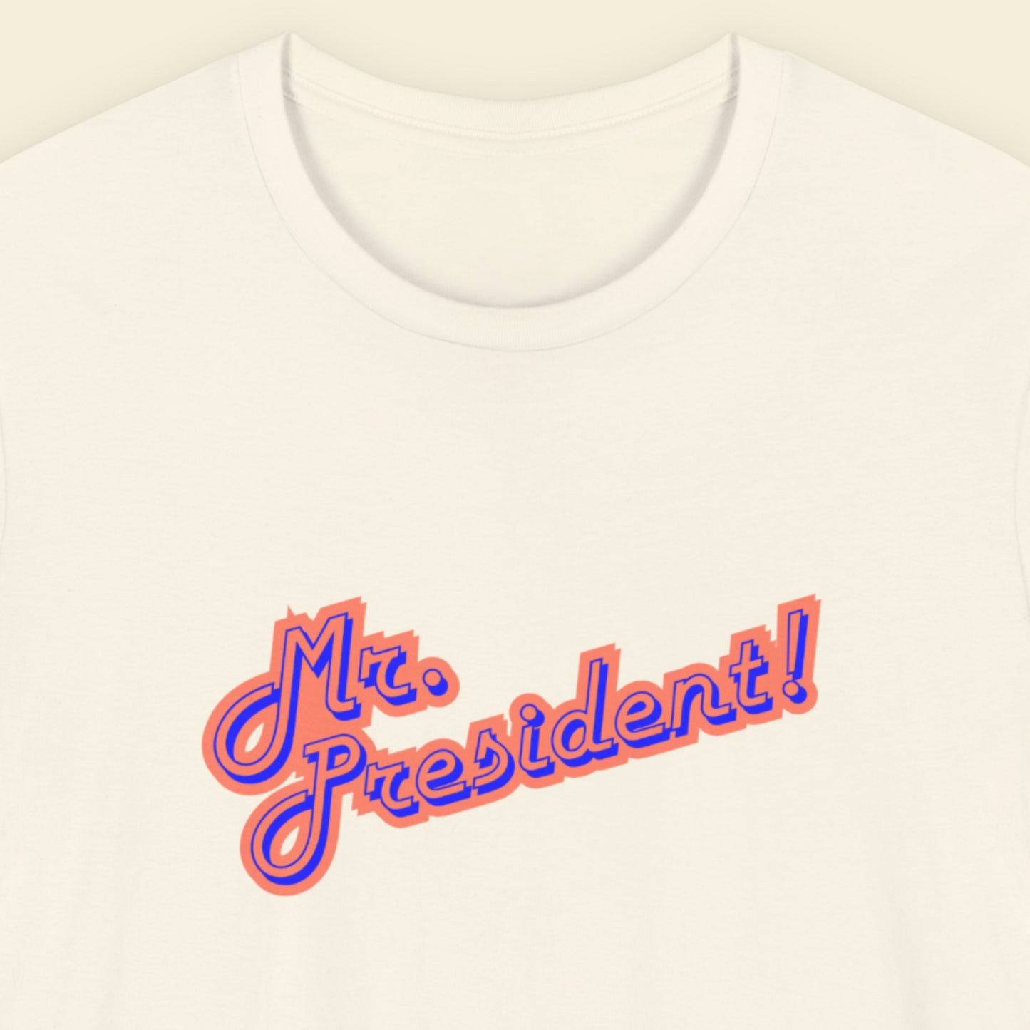 White t-shirt with 'Mr. President!' text in orange and blue on a beige background