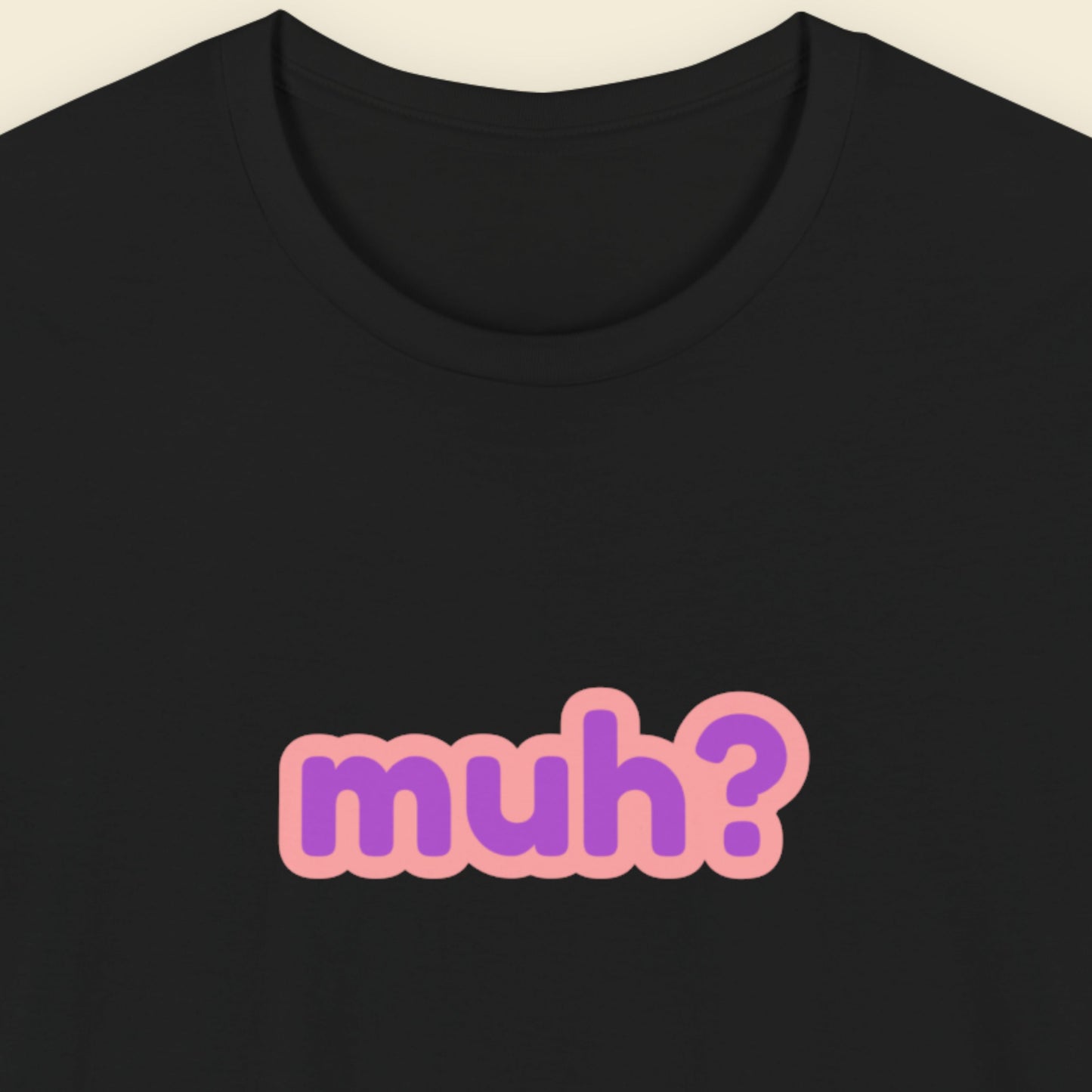 Black t-shirt with multicolored 'muh?' text on a beige background.