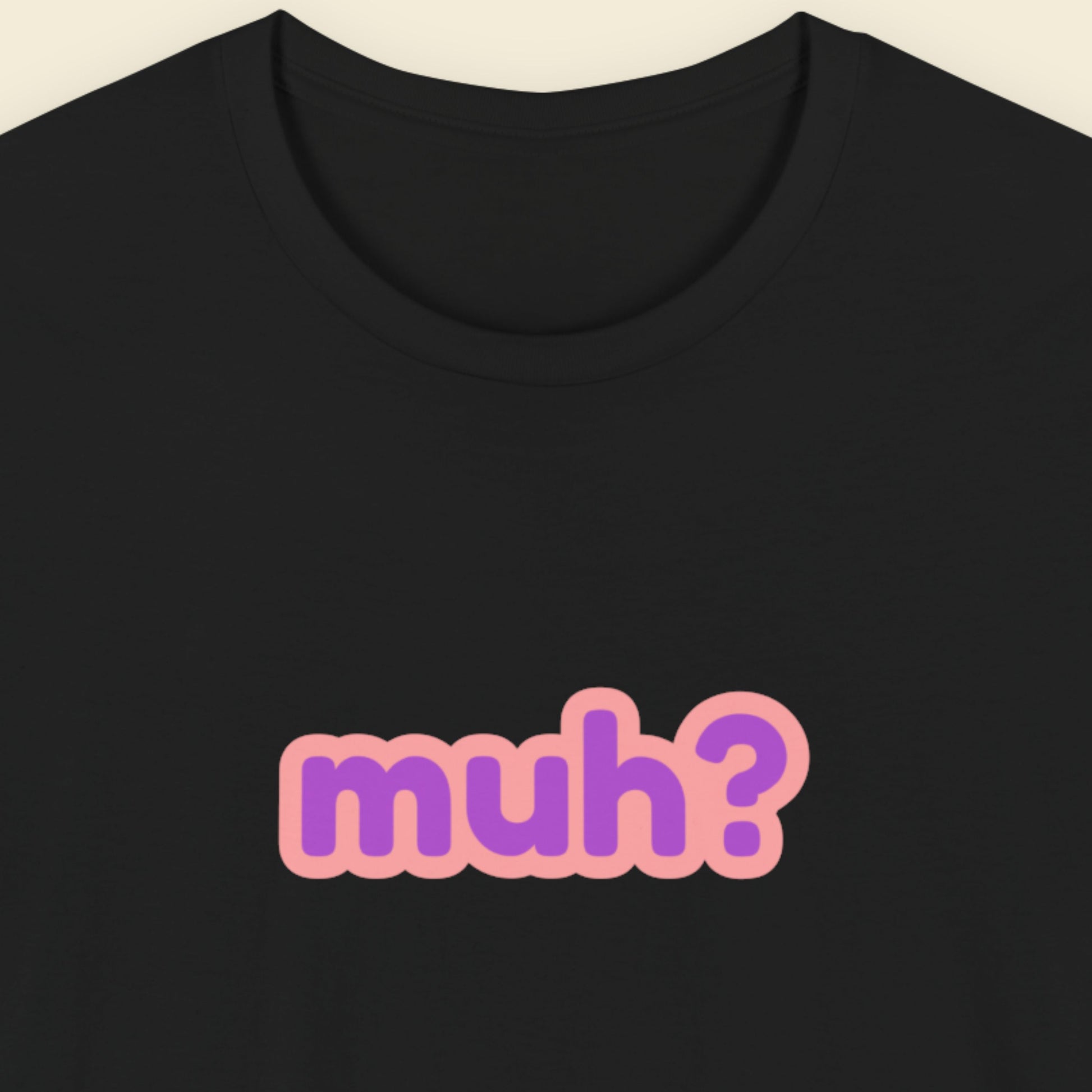 Black t-shirt with multicolored 'muh?' text on a beige background.