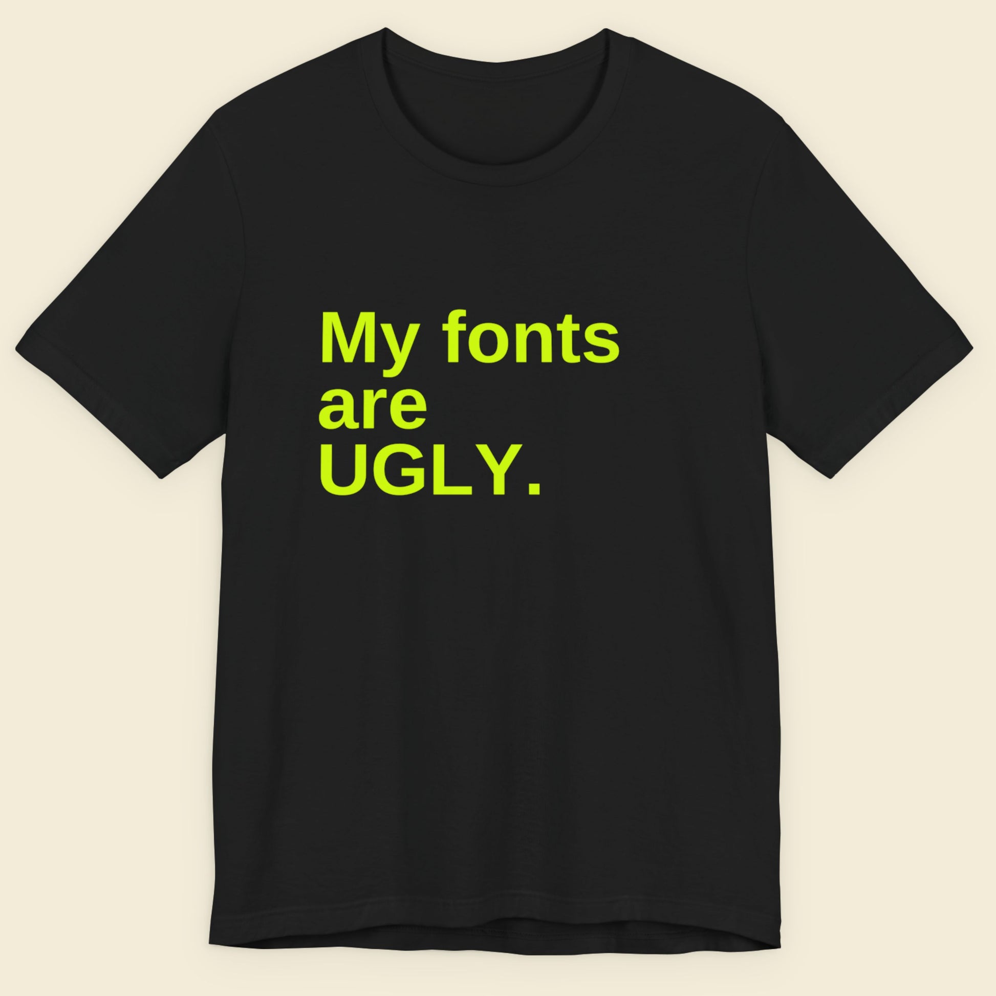Black t-shirt with yellow text 'My fonts are UGLY.' on a beige background.