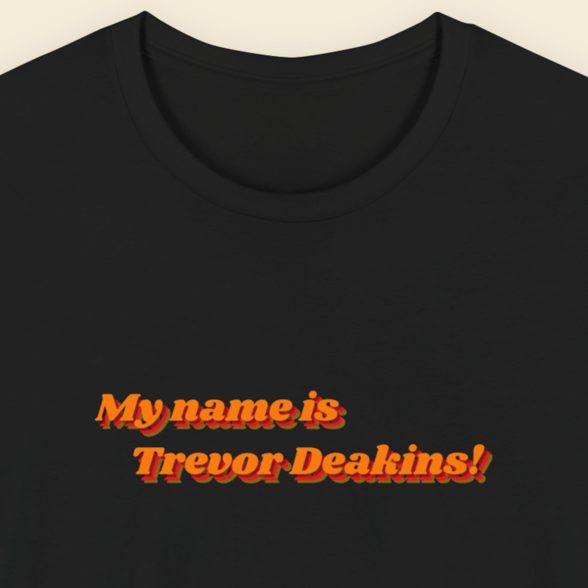 Black t-shirt with red text 'My name is Trevor Deakins!' on a beige background