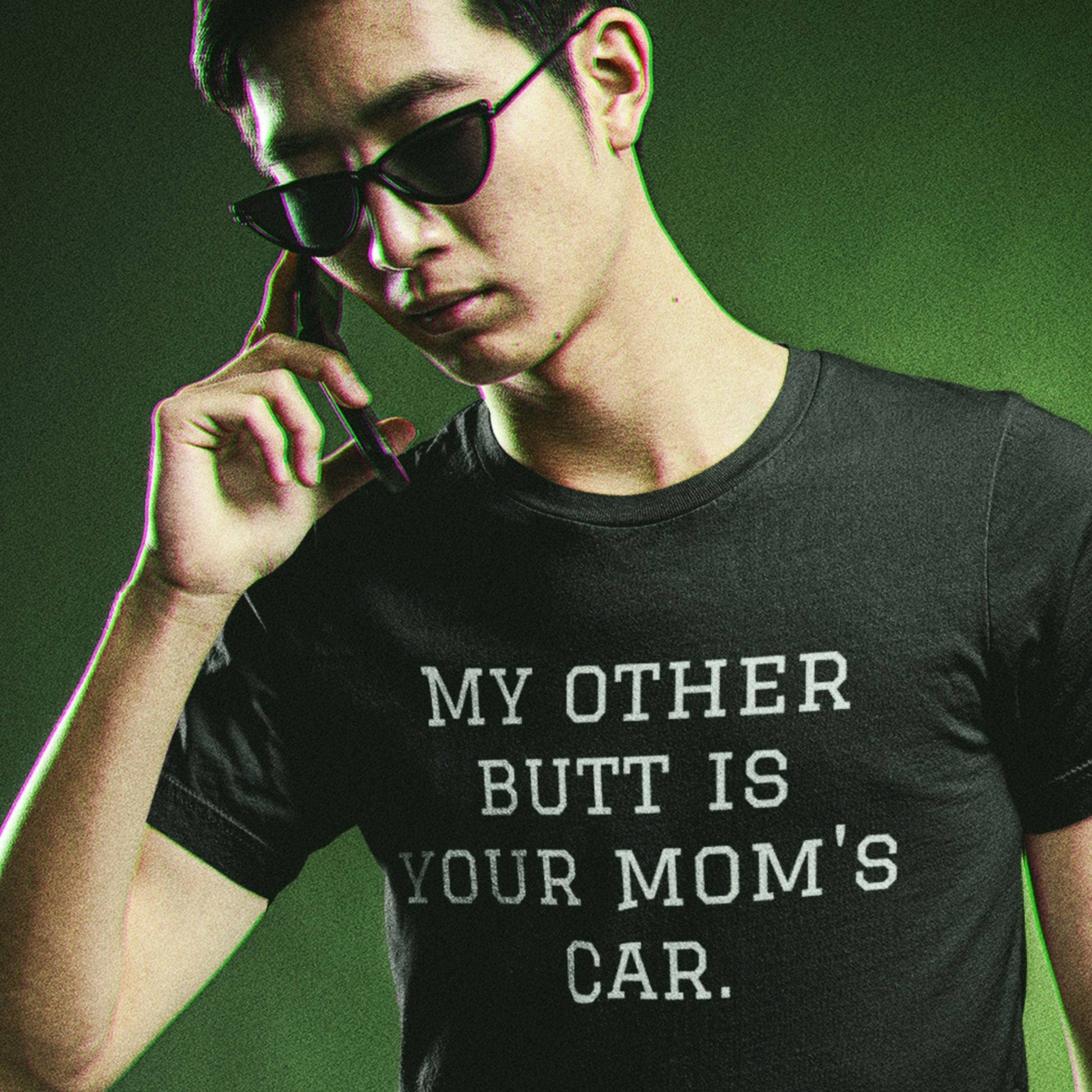Man wearing sunglasses and a black t-shirt with humorous text on a green background.