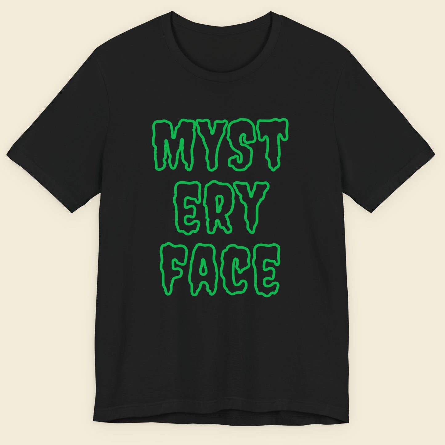 Black t-shirt with green text 'MYSTERY FACE' on a beige background.
