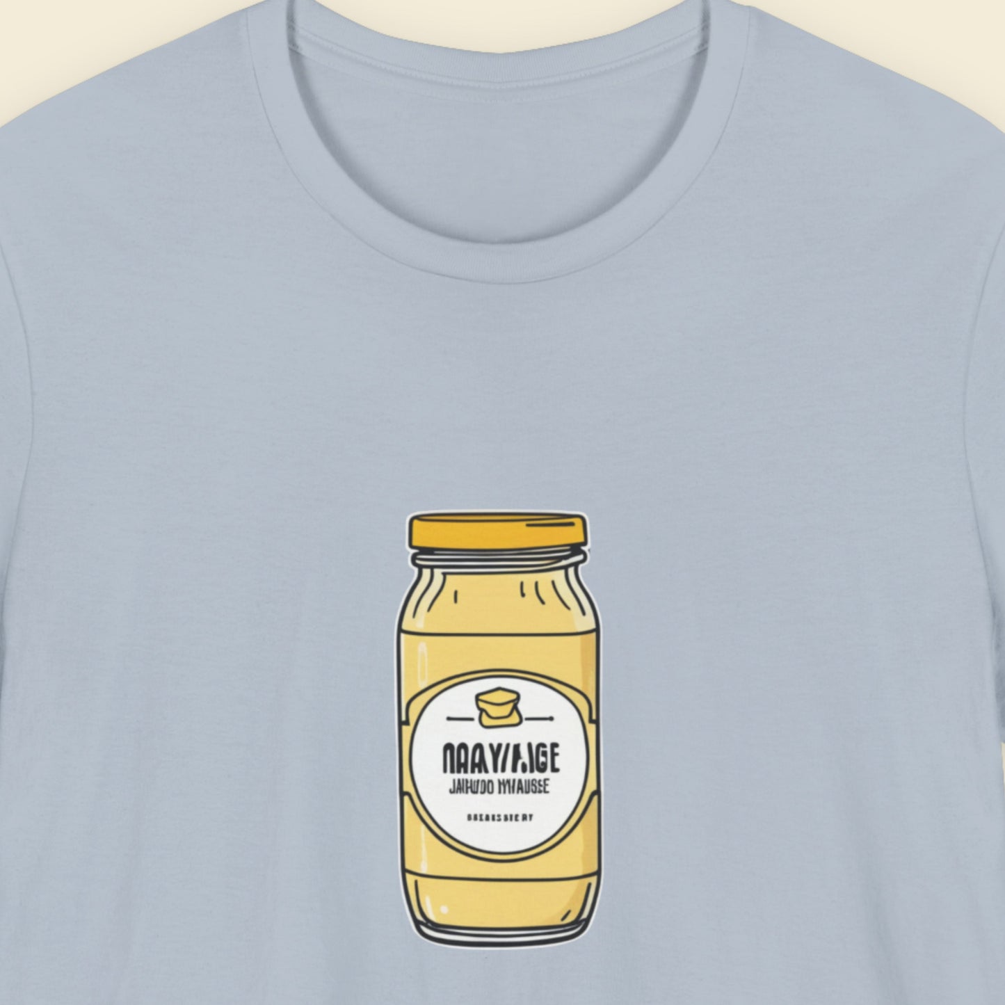 Light blue shirt with a drawing of a jar of specialty Dijonaise against a beige background.