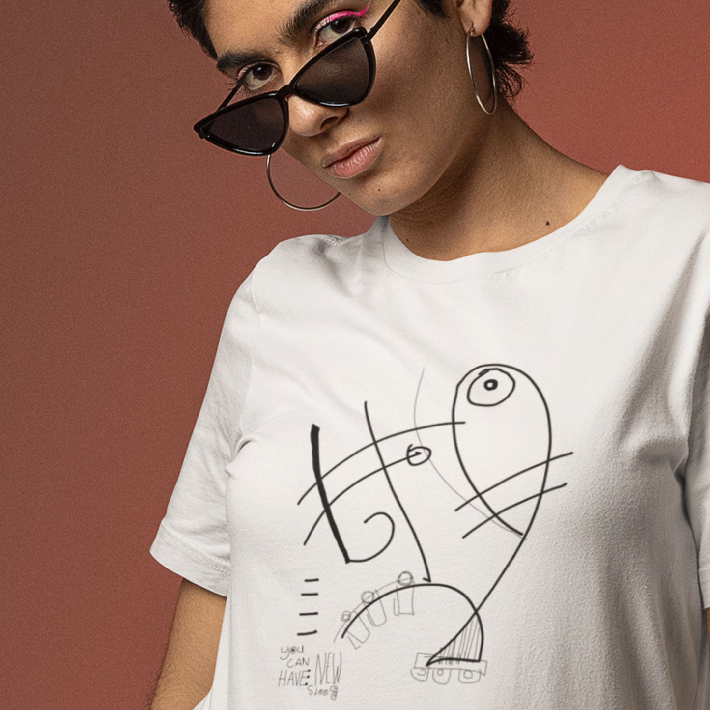 Person wearing a white t-shirt with abstract design on a brown background.